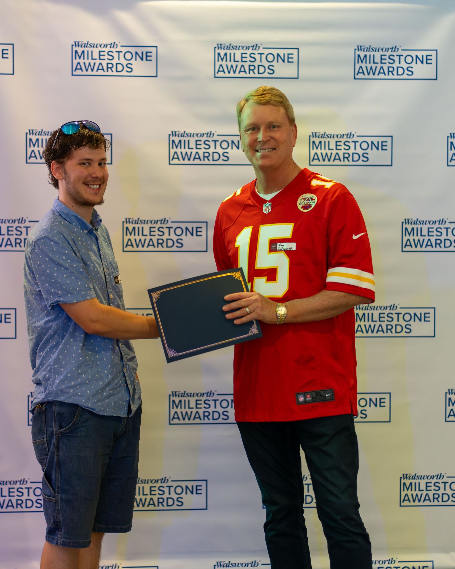 People in Kansas City Chiefs jerseys pose for photos at an awards ceremony with Milestone Awards backdrop.