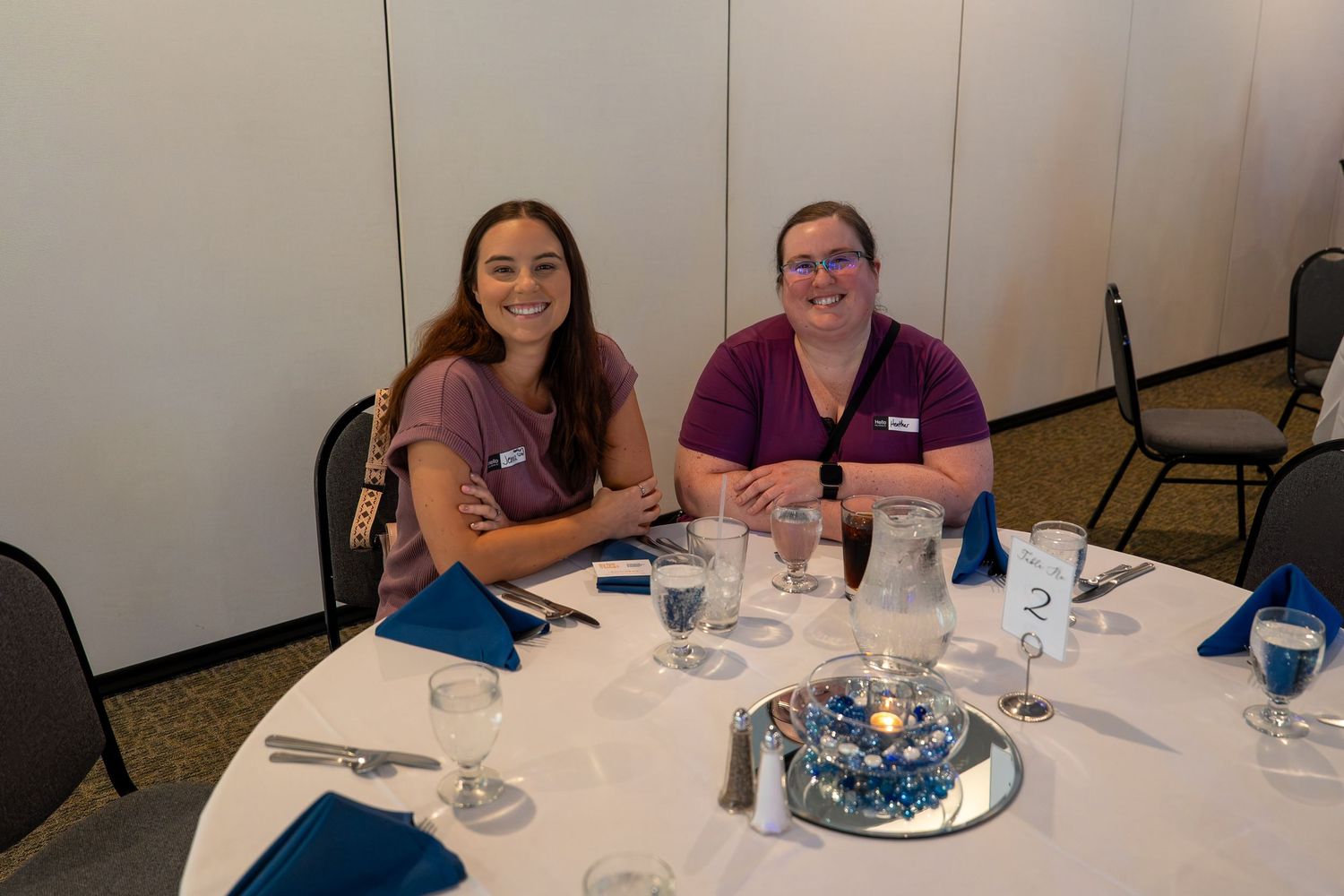 Group of people sitting around a table at a celebration with cake and drinks.