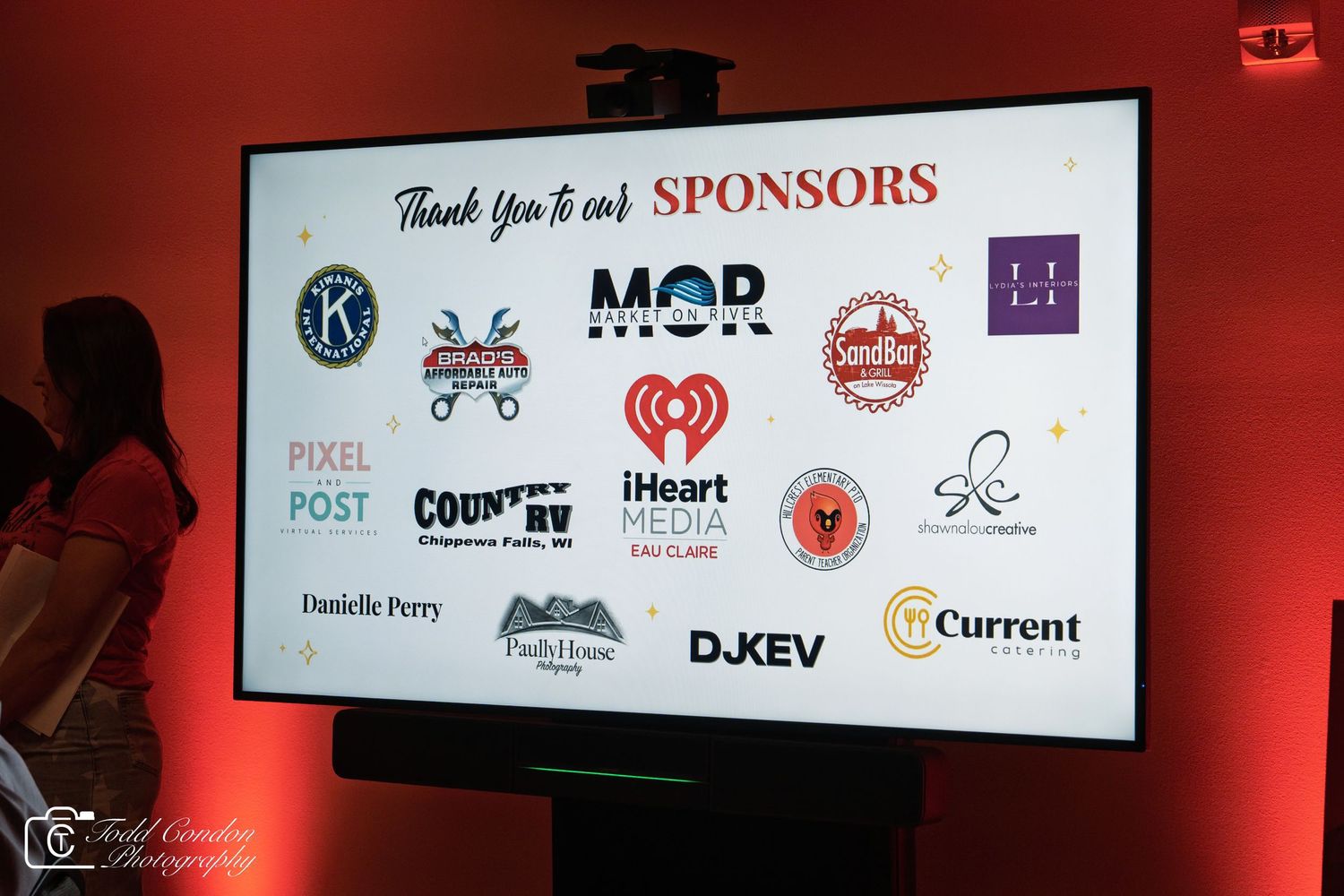 Event sponsors slide displayed on screen at a red-lit venue showing logos including iHeart Media, MOR, and Country RV.