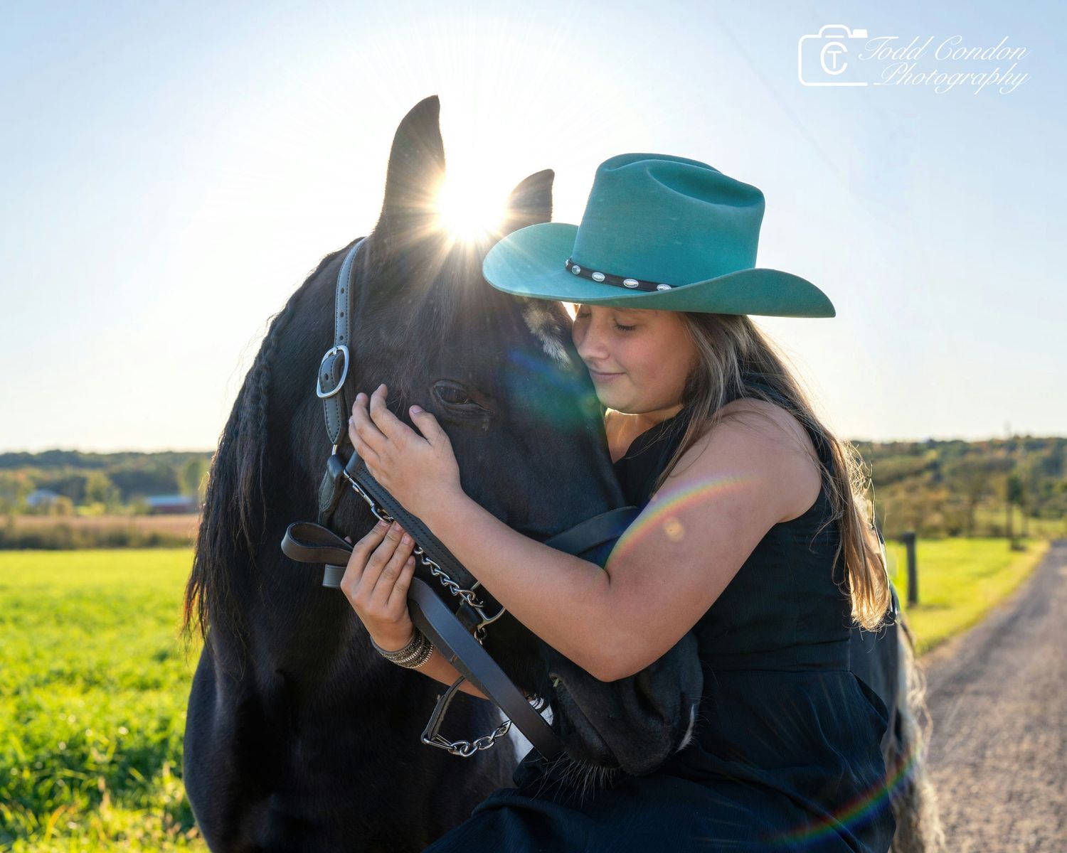 A romantic couple in cowboy hats embrace in a sunlit field of yellow wildflowers during golden hour.