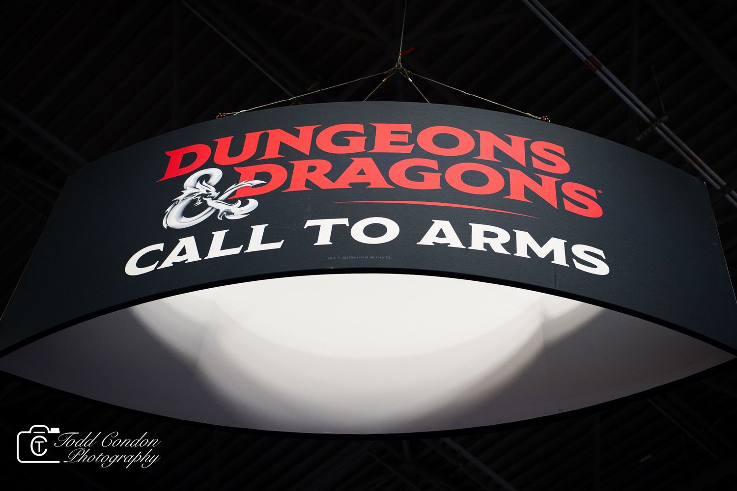 Illuminated Dungeons & Dragons Call to Arms sign hanging from ceiling at a gaming convention.