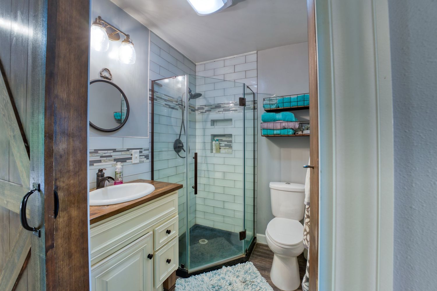 Modern farmhouse bathroom with walk-in glass shower, white subway tiles, vanity, and toilet.
