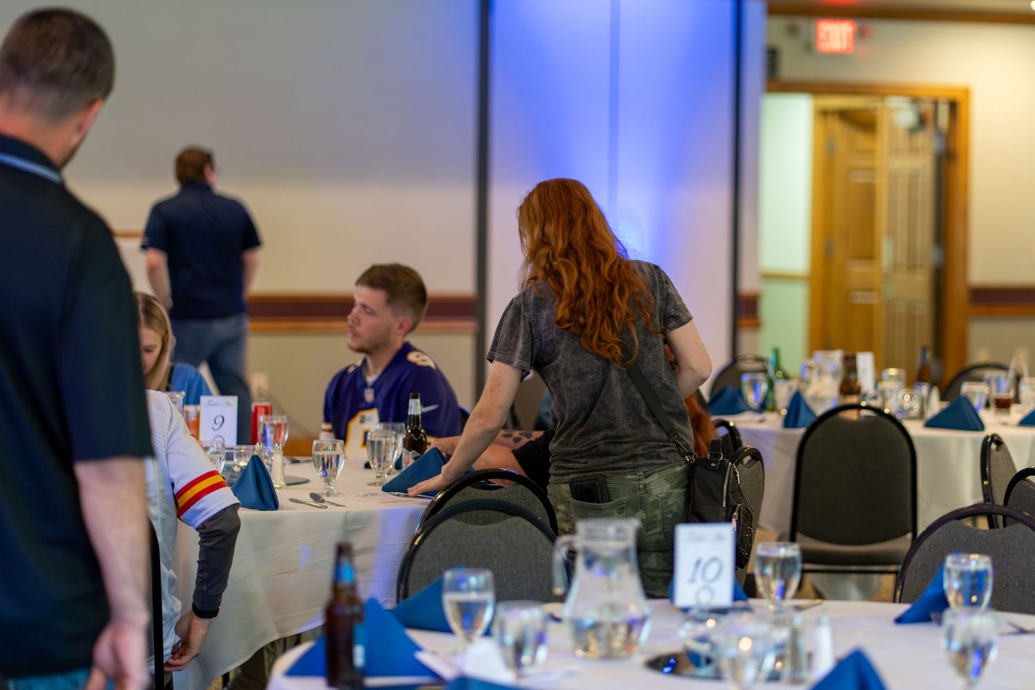 Business professionals seated at round tables during a conference or training event in a meeting room.