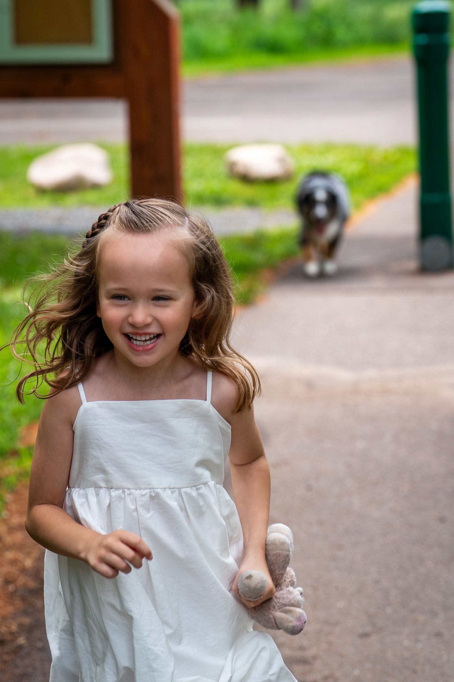 White dress flowing in motion against green outdoor background.