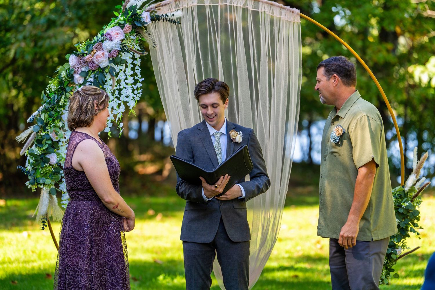 A couple shares a tender moment during their outdoor garden wedding ceremony beneath a floral archway.