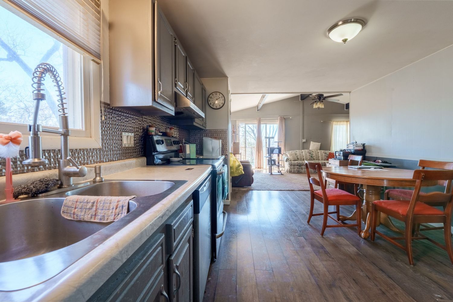 Modern open concept living area with wood floors and natural lighting from large windows.