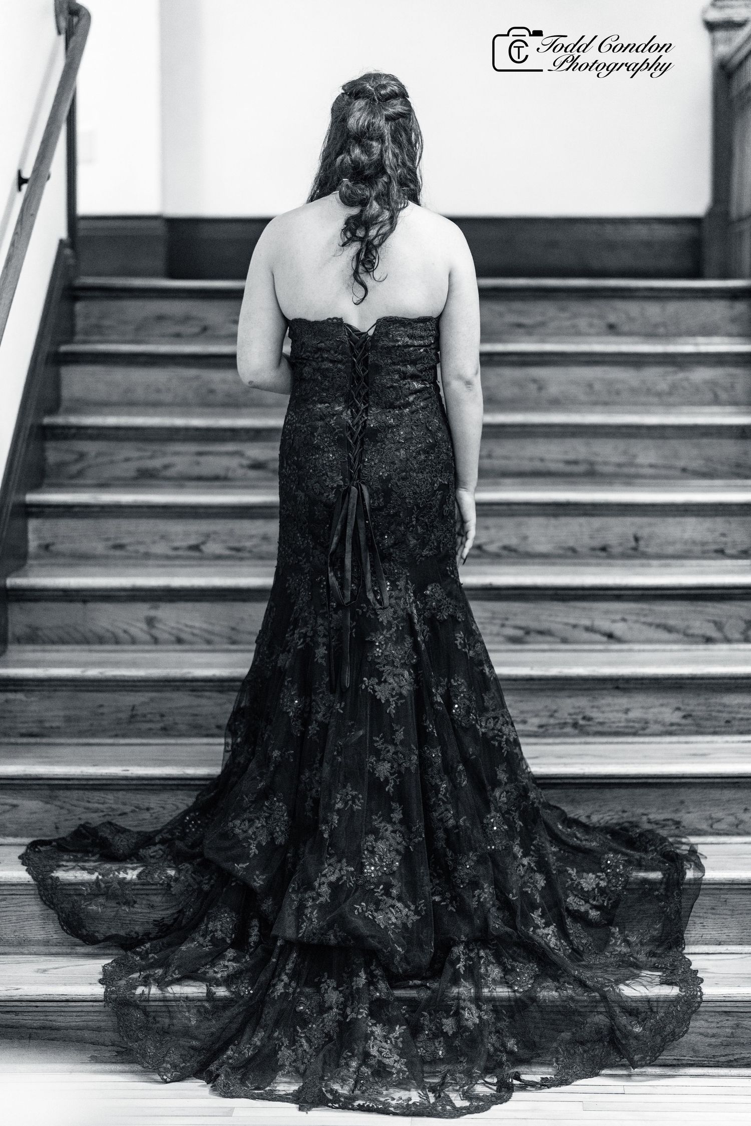 A black lace formal gown with a flowing train is showcased in a series of artistic black and white photographs on stairs.