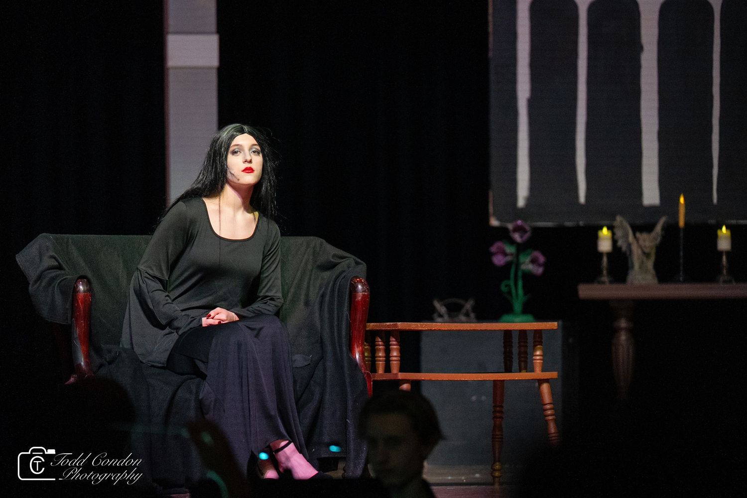 Dramatic stage performance with dark lighting and gothic arches in the background.