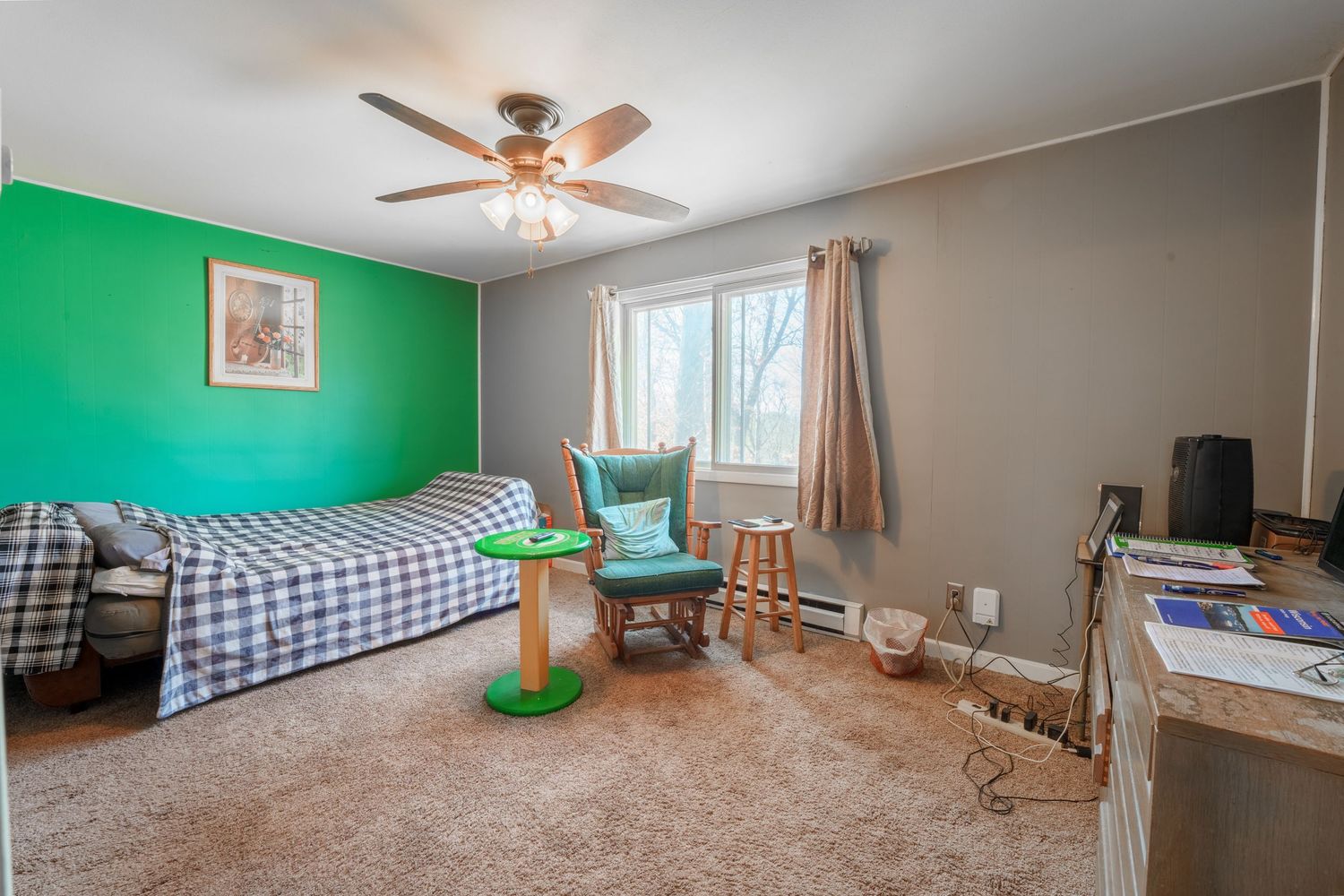 Empty room with beige carpet, ceiling fan, and bright green accent wall.