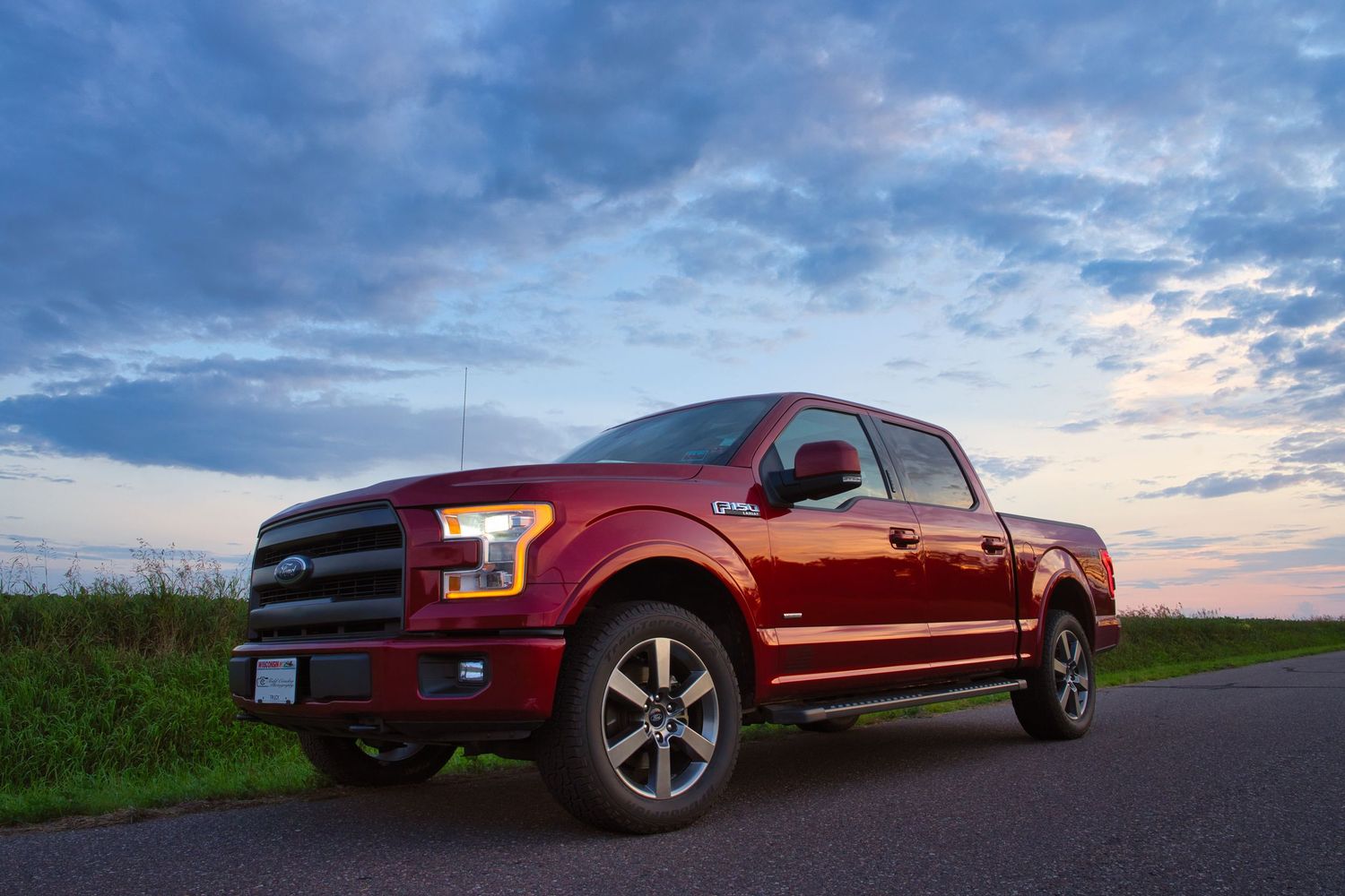 Red Ford F-150 pickup truck photographed at sunset against dramatic blue sky and rural landscape.