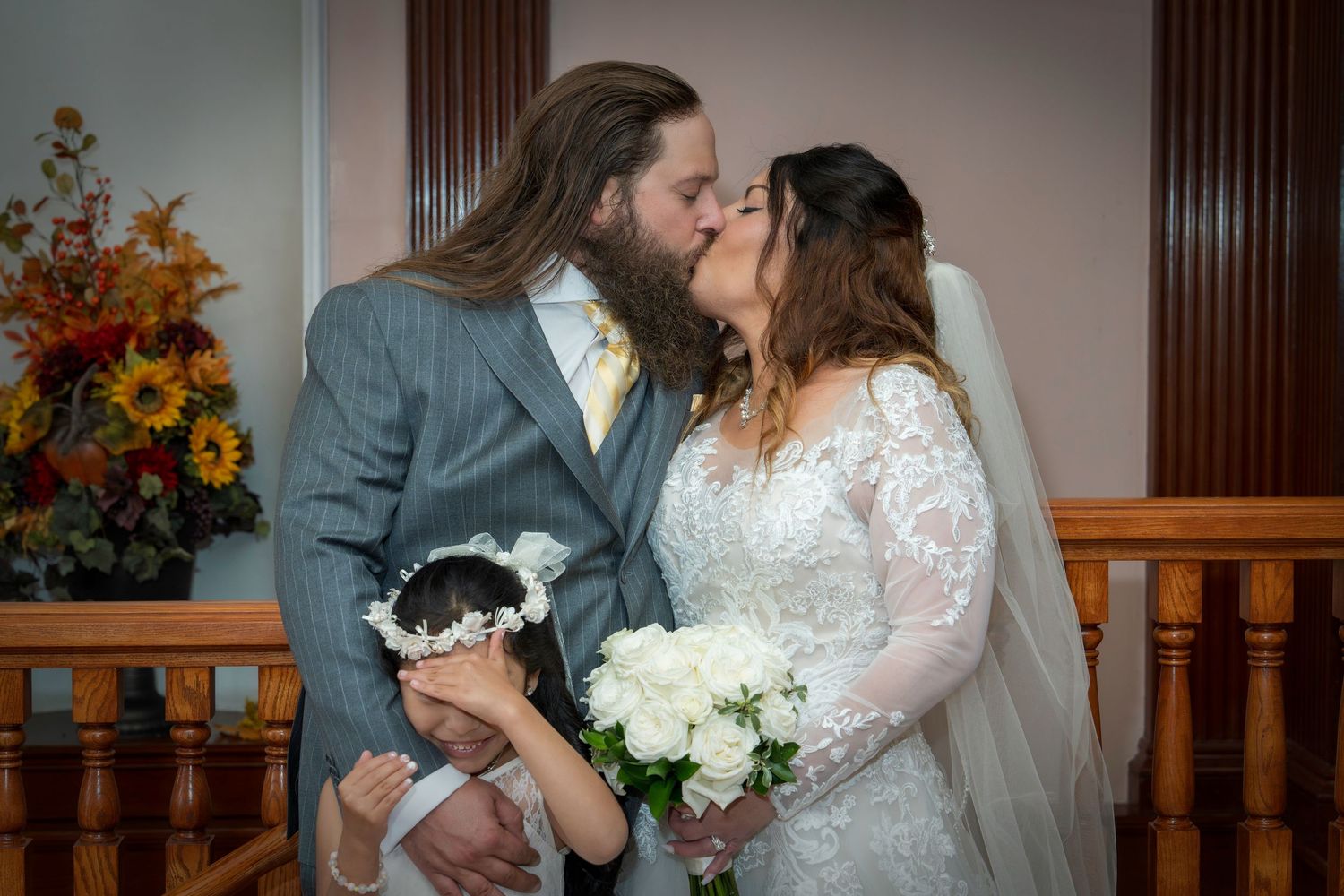 Newlyweds share intimate moments during their wedding celebration with autumn floral decor in the background.