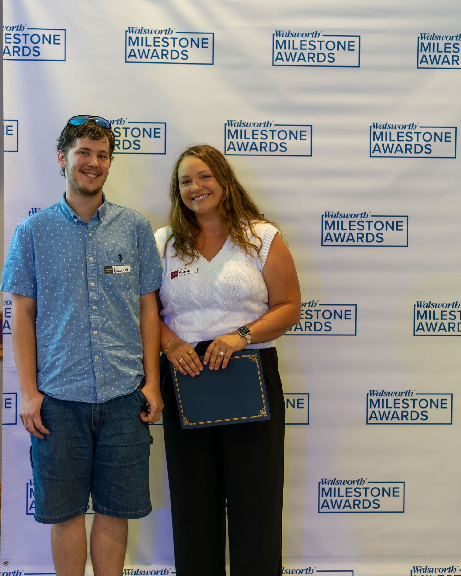 Group of people standing against a branded step-and-repeat wall with Milestone Awards logos at an event.
