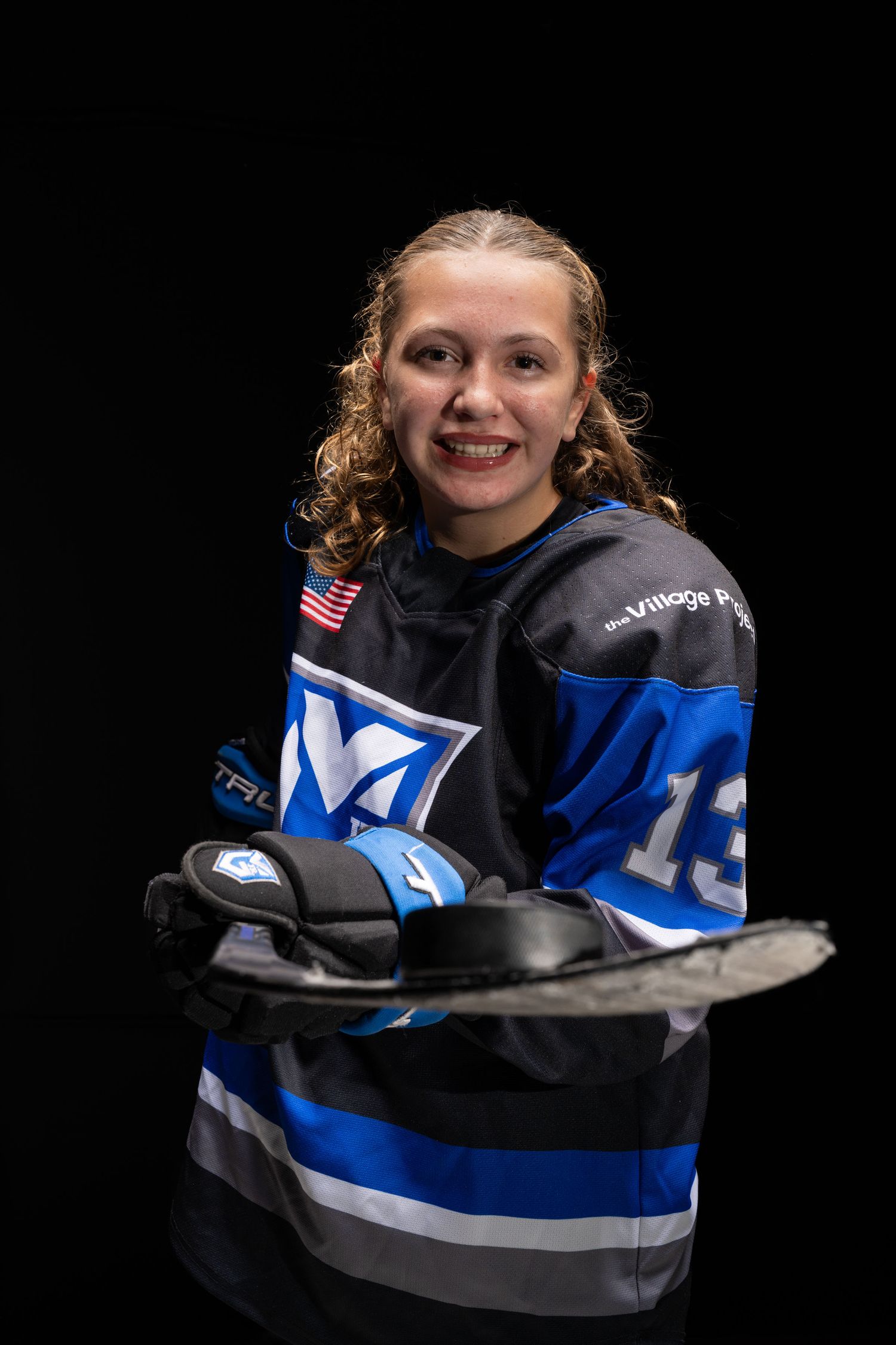 A series of four photos showing someone wearing a blue and black hockey jersey against a dark background.