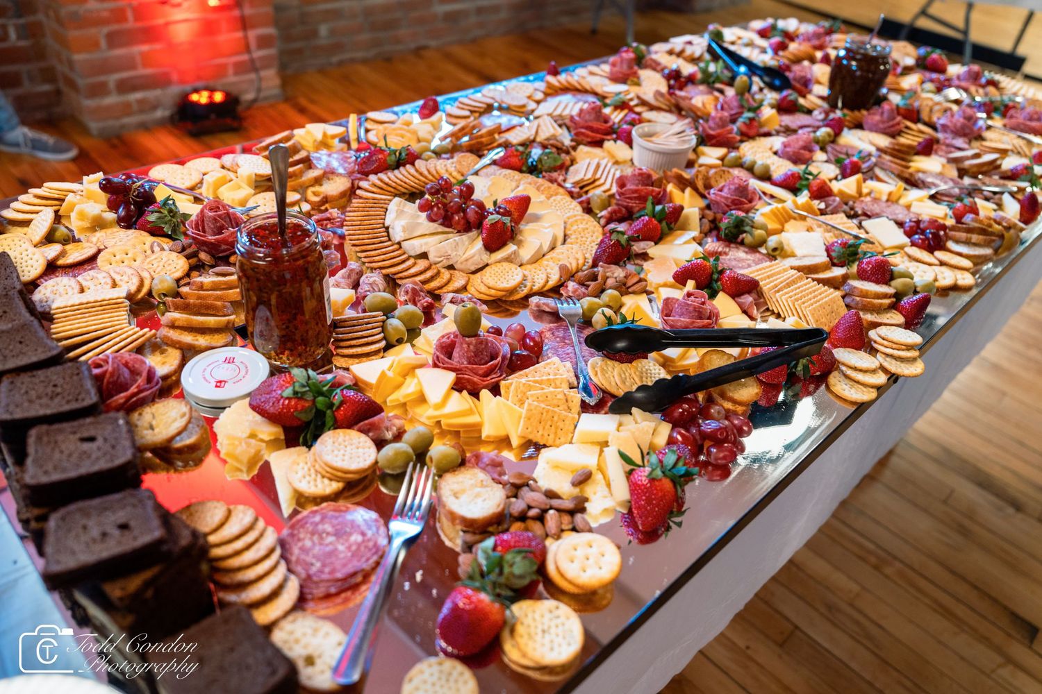 Elegant charcuterie board with assorted cheeses, crackers, meats, strawberries, and nuts displayed on a mirrored table.
