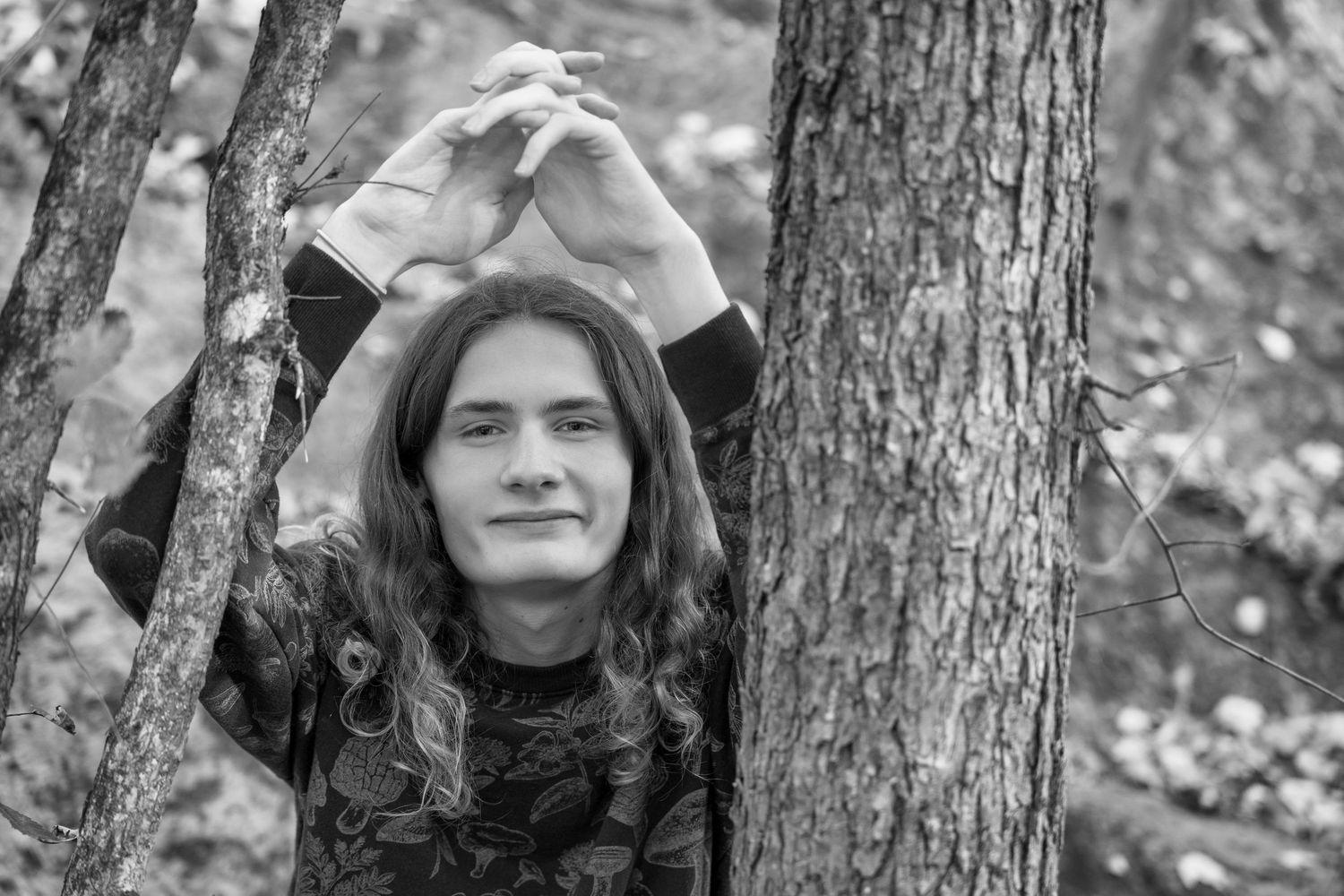 Black and white portrait photos arranged in a row showing people posing behind tree trunks in a forest setting.