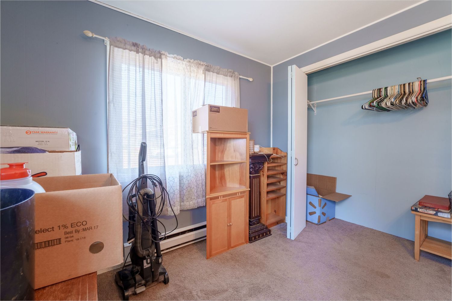 Long view of an empty room with blue walls and wooden furniture against the walls.