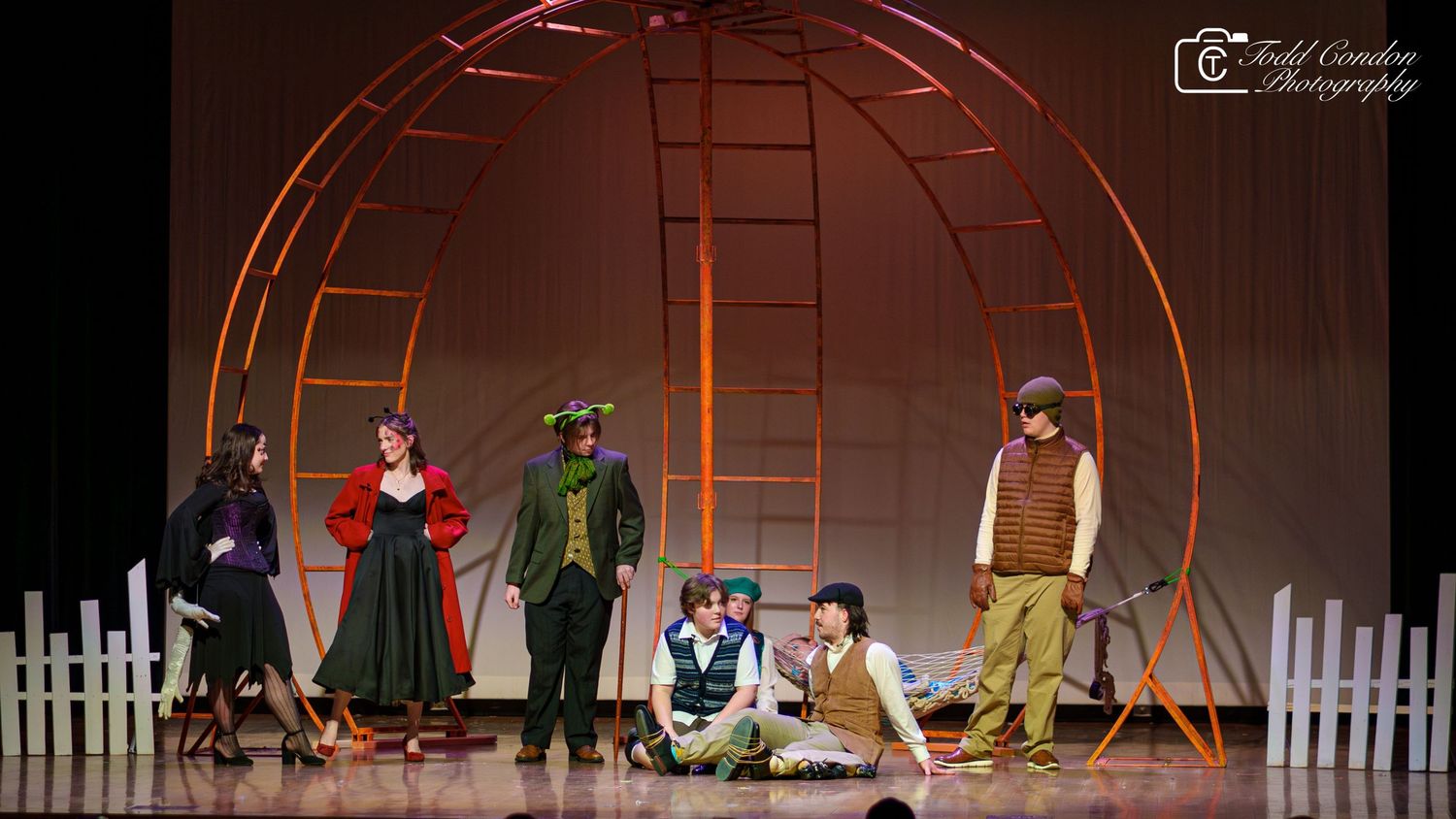A dance performance on stage with orange lighting and geometric set pieces featuring multiple performers in motion.