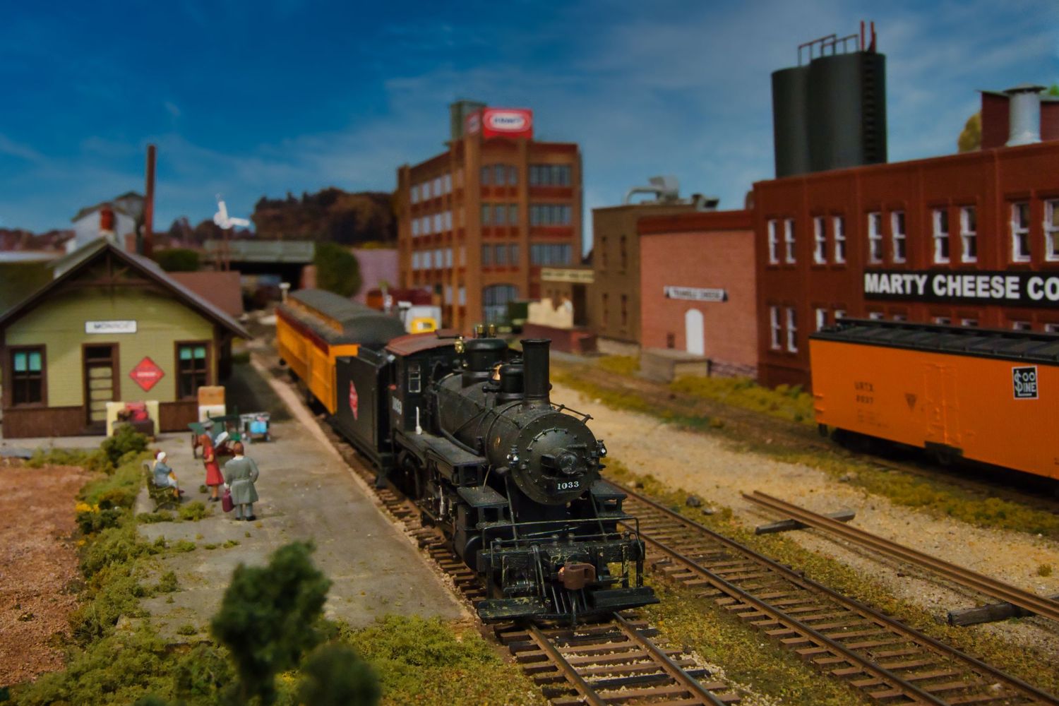 Detailed miniature railroad diorama showcasing industrial buildings and train tracks in an urban setting.