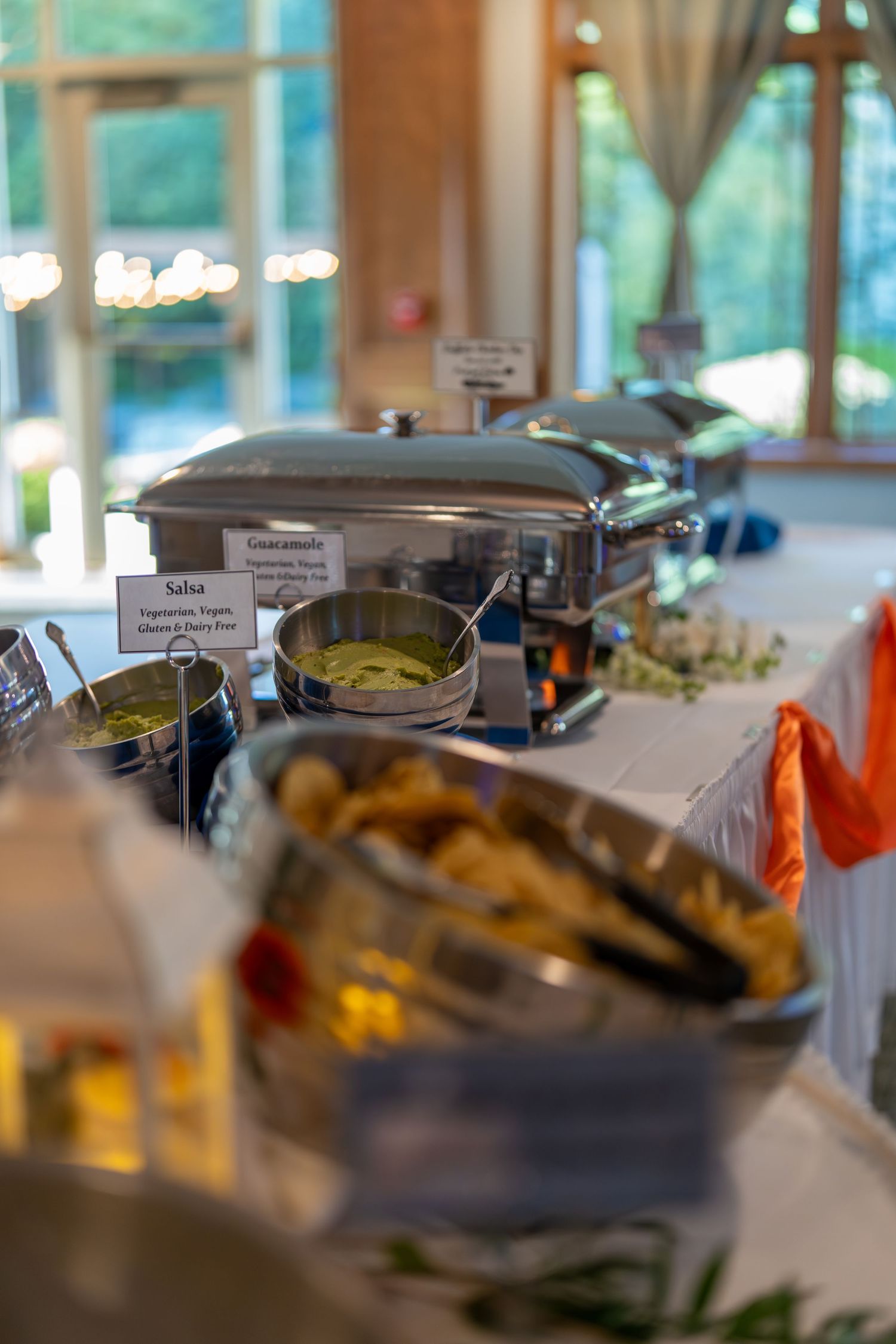 Buffet serving station with chafing dishes and food warmers set up for catering at an indoor event venue.