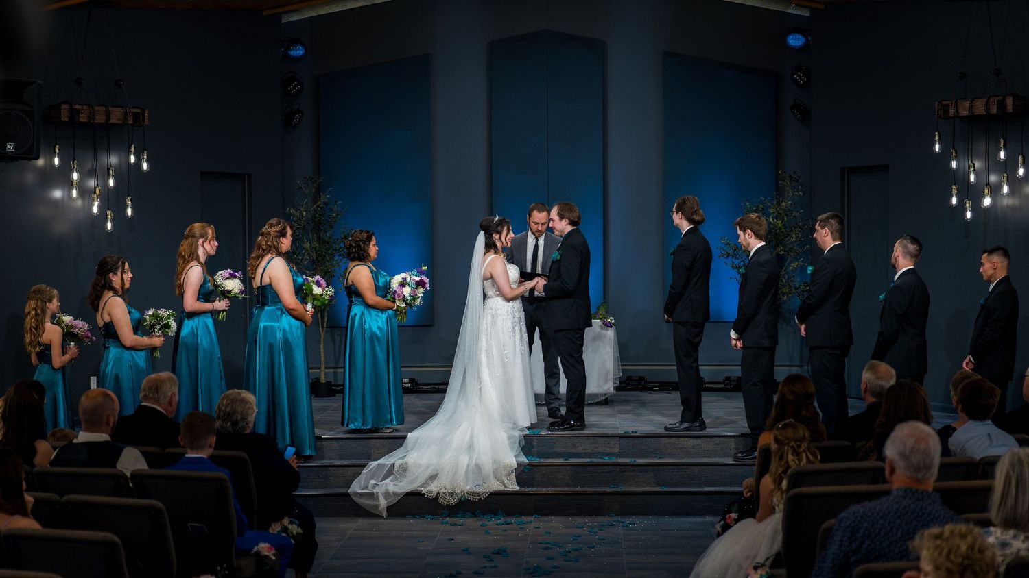 Wedding reception venue with elegant chandeliers and blue mood lighting creates a romantic atmosphere for celebrations.