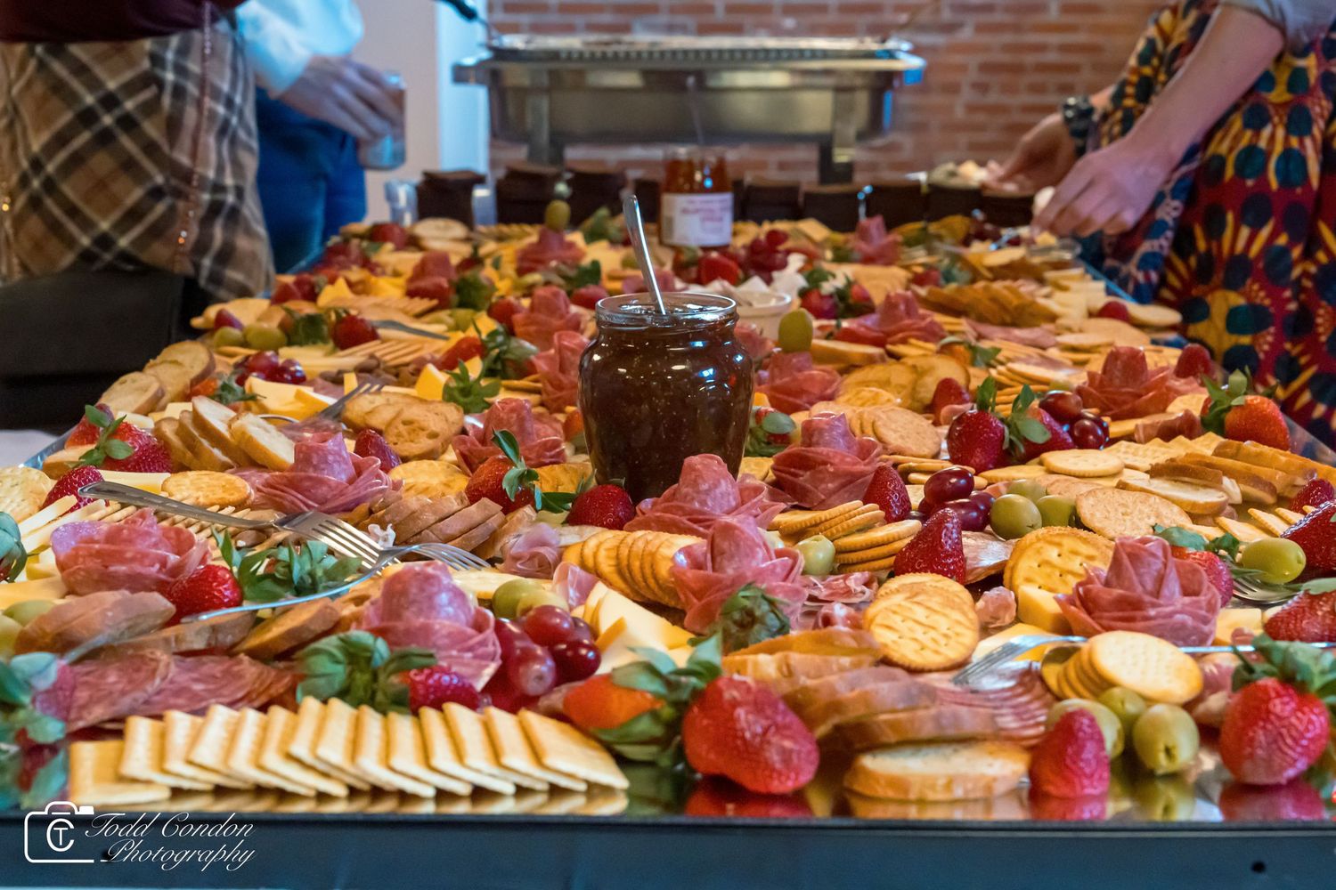 A lavish charcuterie board spread with meats, cheeses, crackers, and fresh strawberries at a catered event.