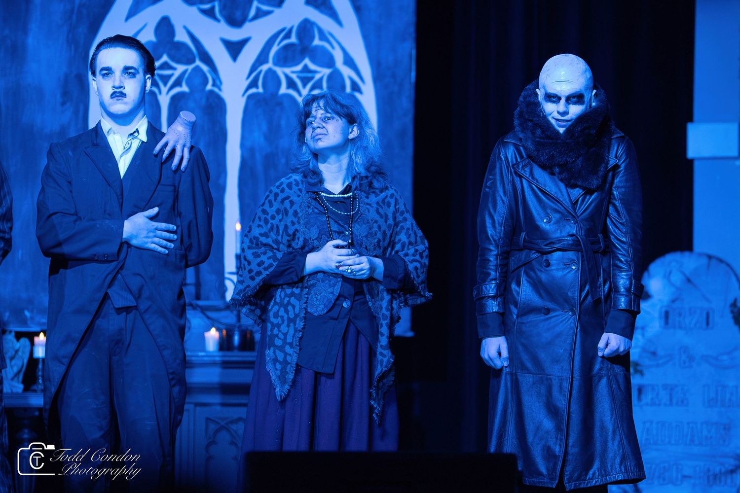 Theatrical performance cast members in dramatic blue lighting on stage during an intense scene.