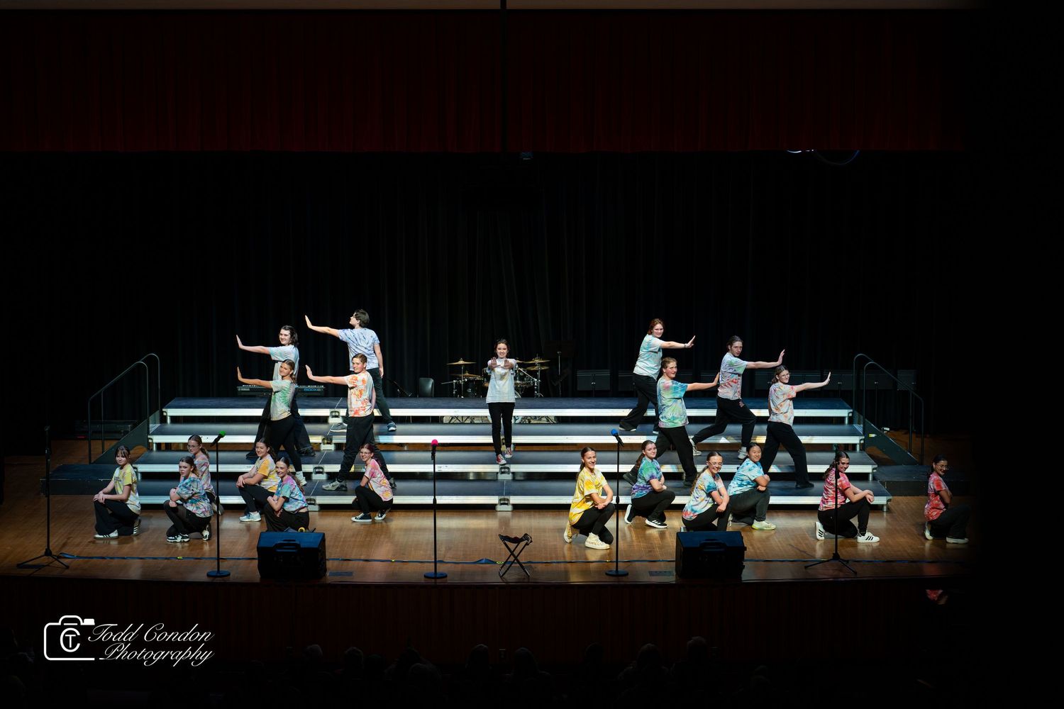 Dancers perform a synchronized modern dance routine on a dimly lit stage with dramatic lighting effects.