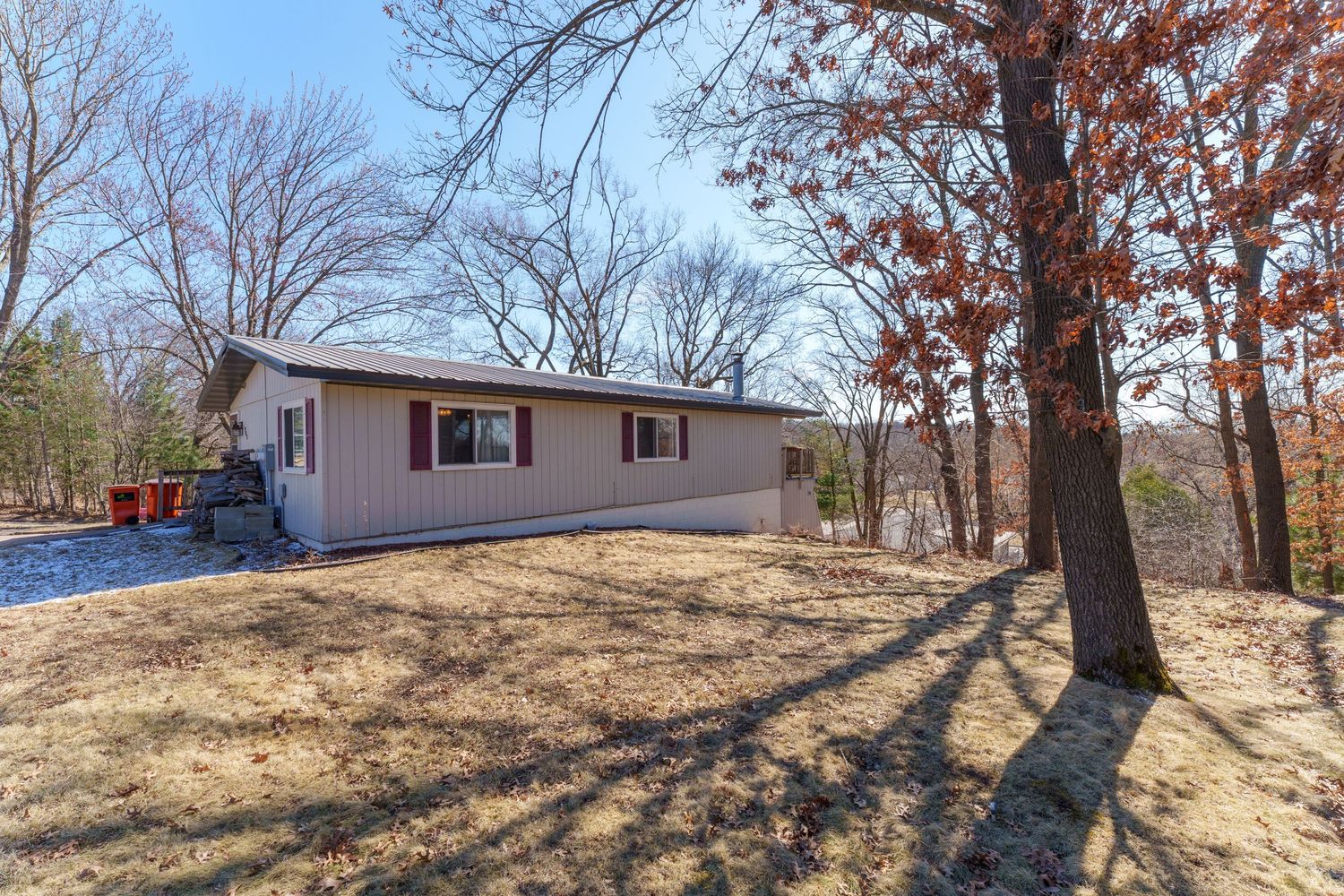 Wide angle view of a hillside property with mobile homes and scattered trees in late fall.