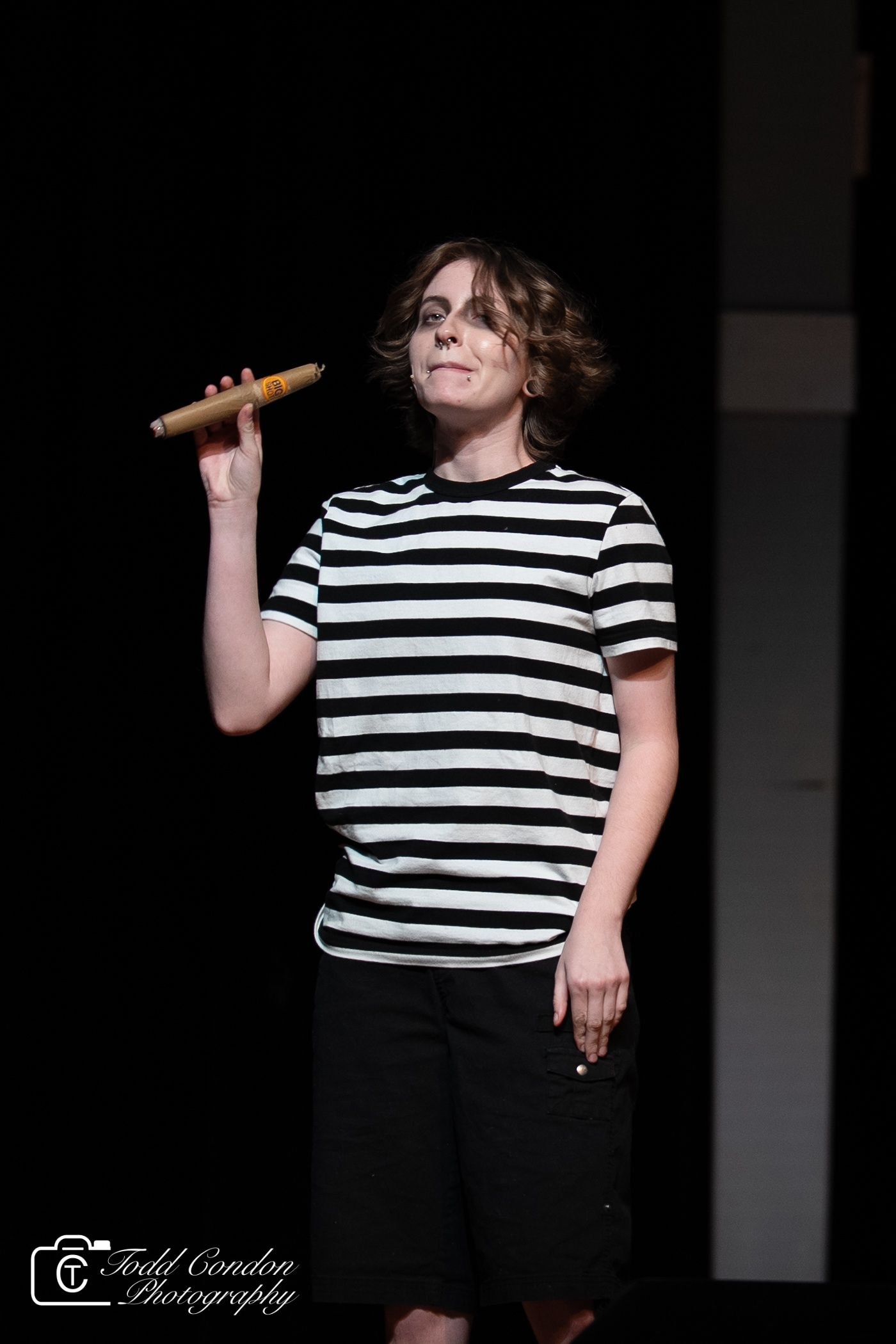 A figure in a black and white striped shirt poses expressively against a dark background in a photo series.