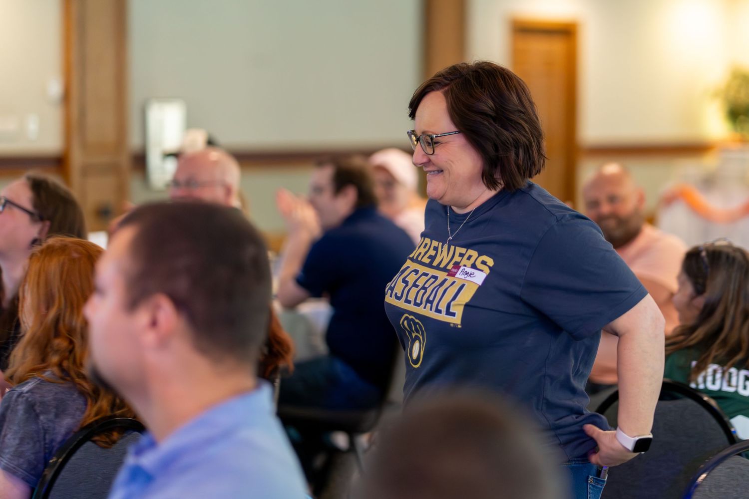People gathered in a conference or meeting room setting with navy blue attire visible in a casual business environment.