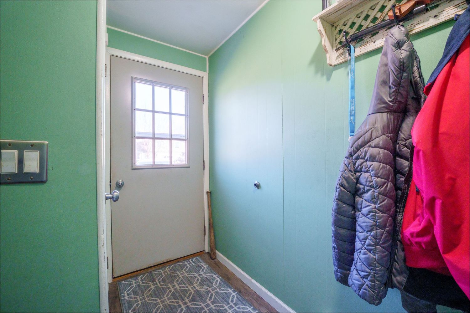 Interior hallway views showing mint green walls and white trim with winter coats hanging on hooks.