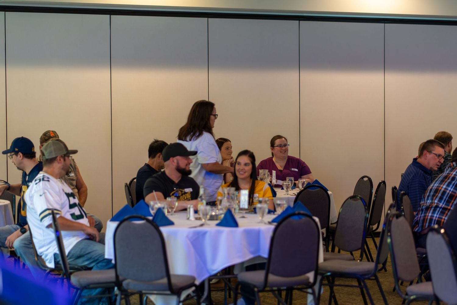 People gather at tables in a conference room during a meeting or event.