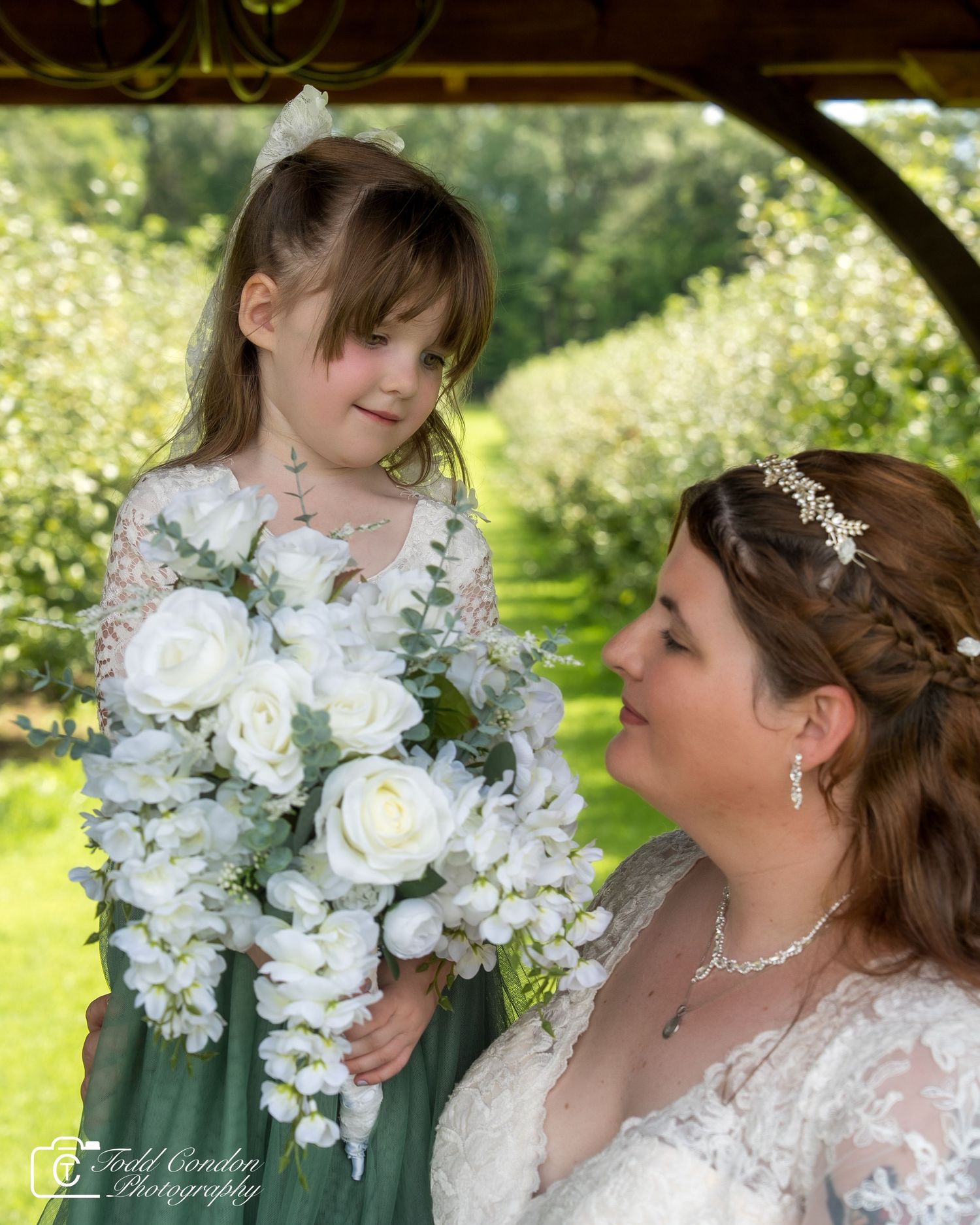 Elegant white bridal bouquet featuring roses and delicate flowers against a natural outdoor garden setting.