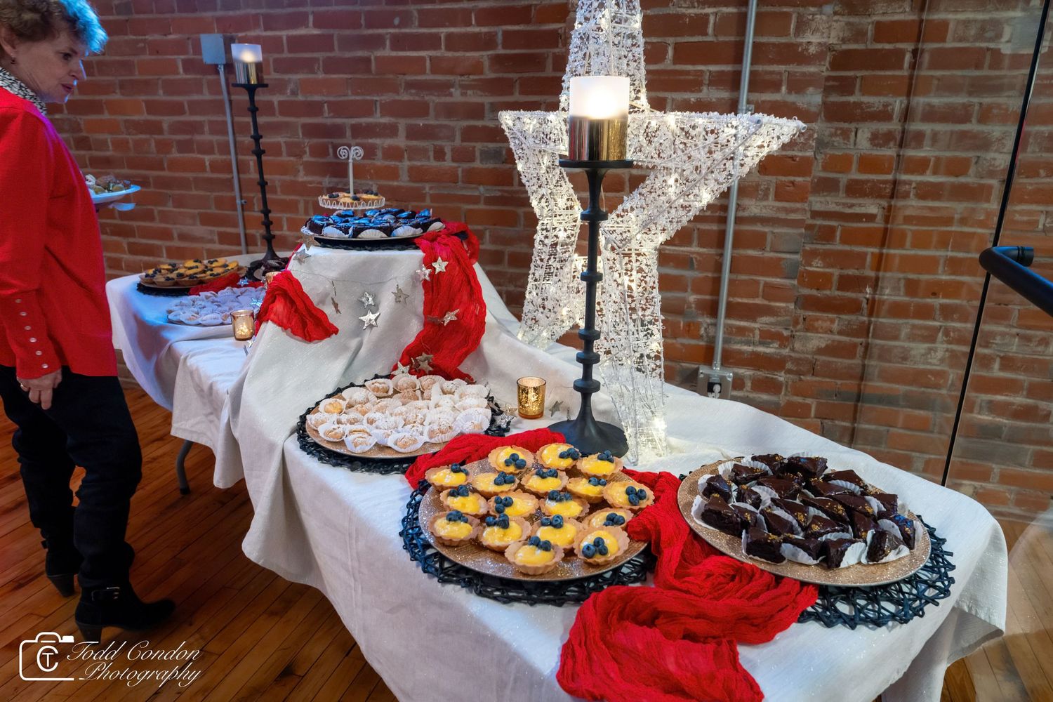 Festive dessert table with assorted cookies and pastries decorated with a star centerpiece at a holiday party.