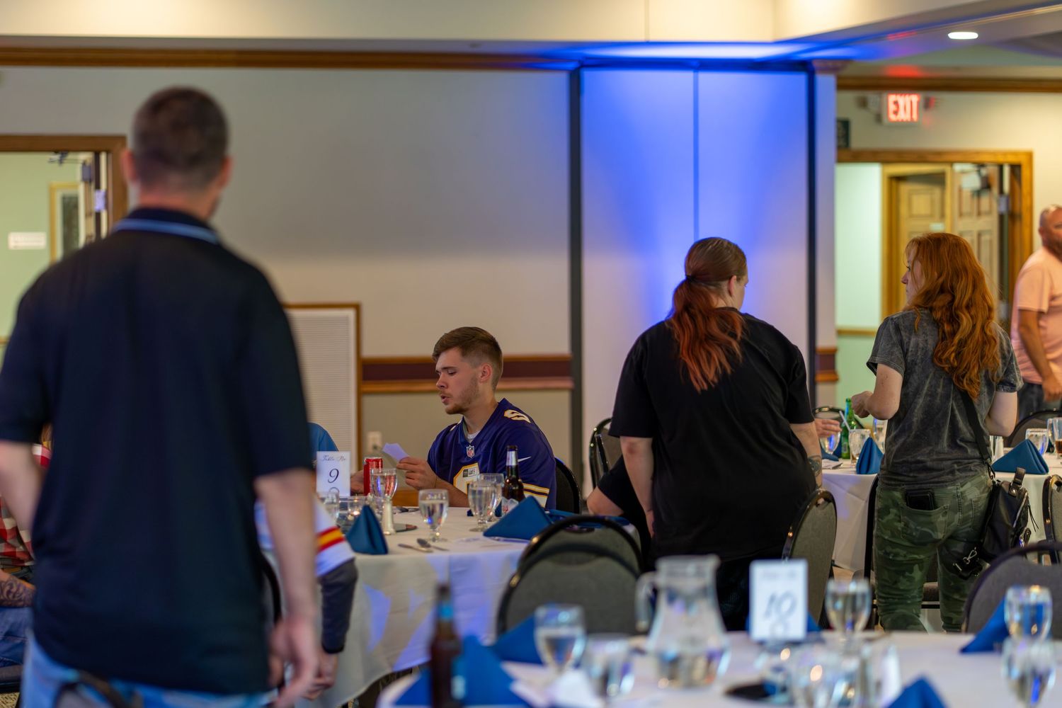 People gather in a conference room with blue lighting for a professional meeting or training session.