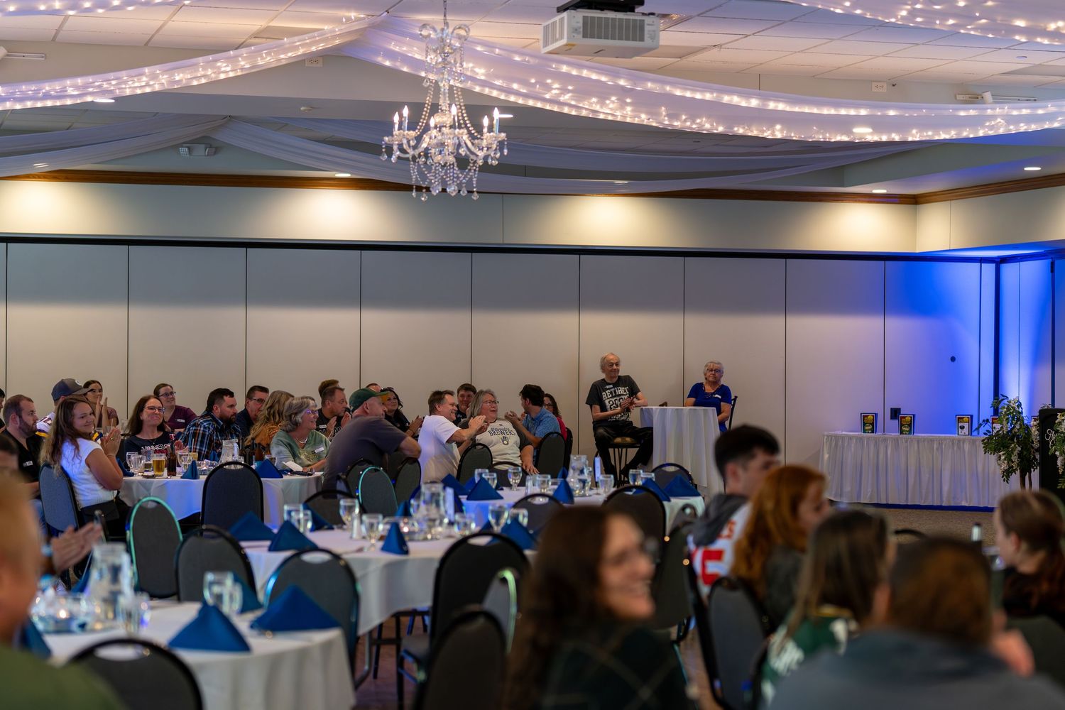 Wedding reception venue decorated with blue uplighting and white tablecloths for an elegant evening celebration.