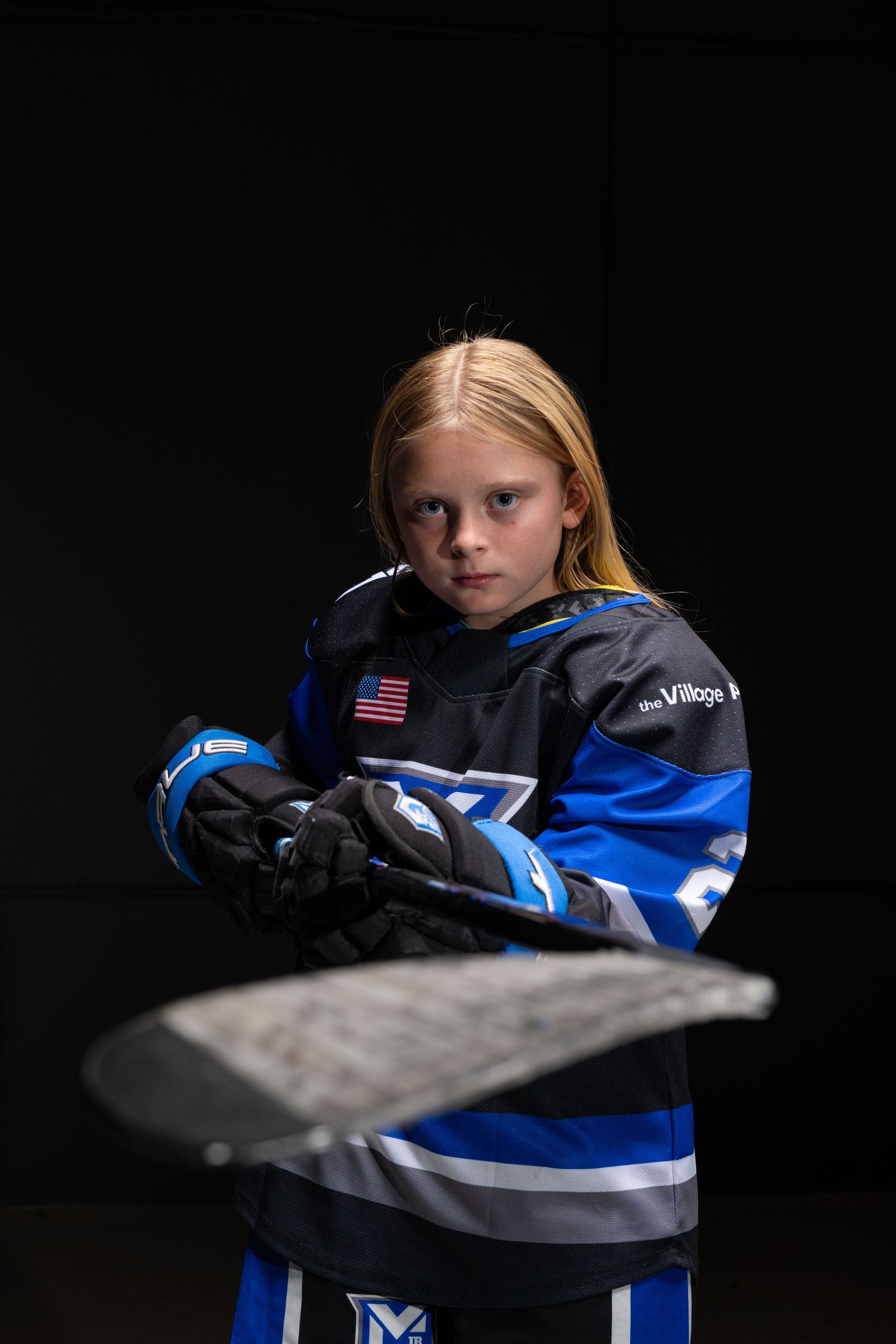 A series of dramatic sports portraits showing a young athlete in blue and black hockey gear against a dark background.