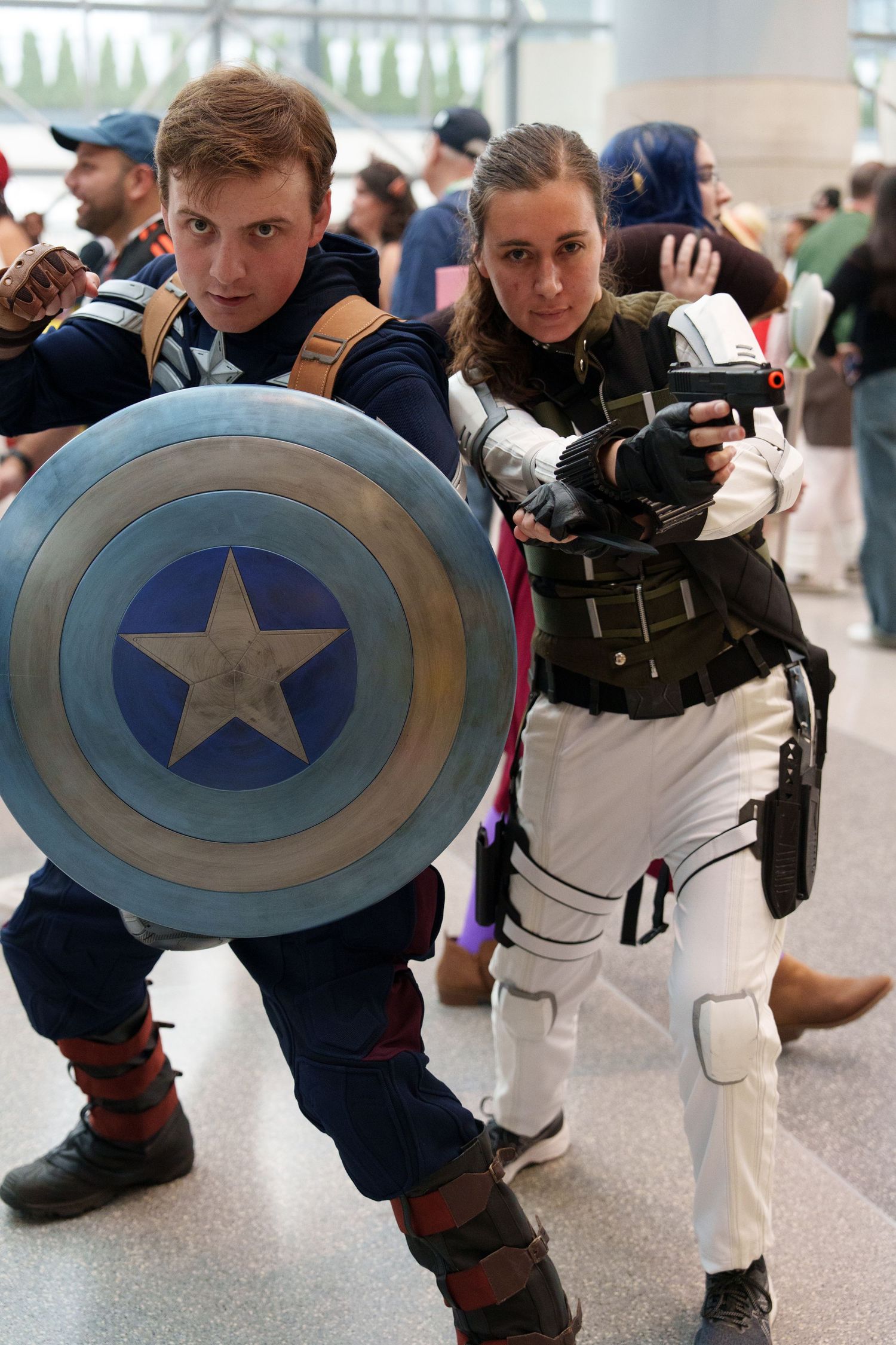 Two cosplayers dressed as Captain America and Black Widow pose at a comic convention.