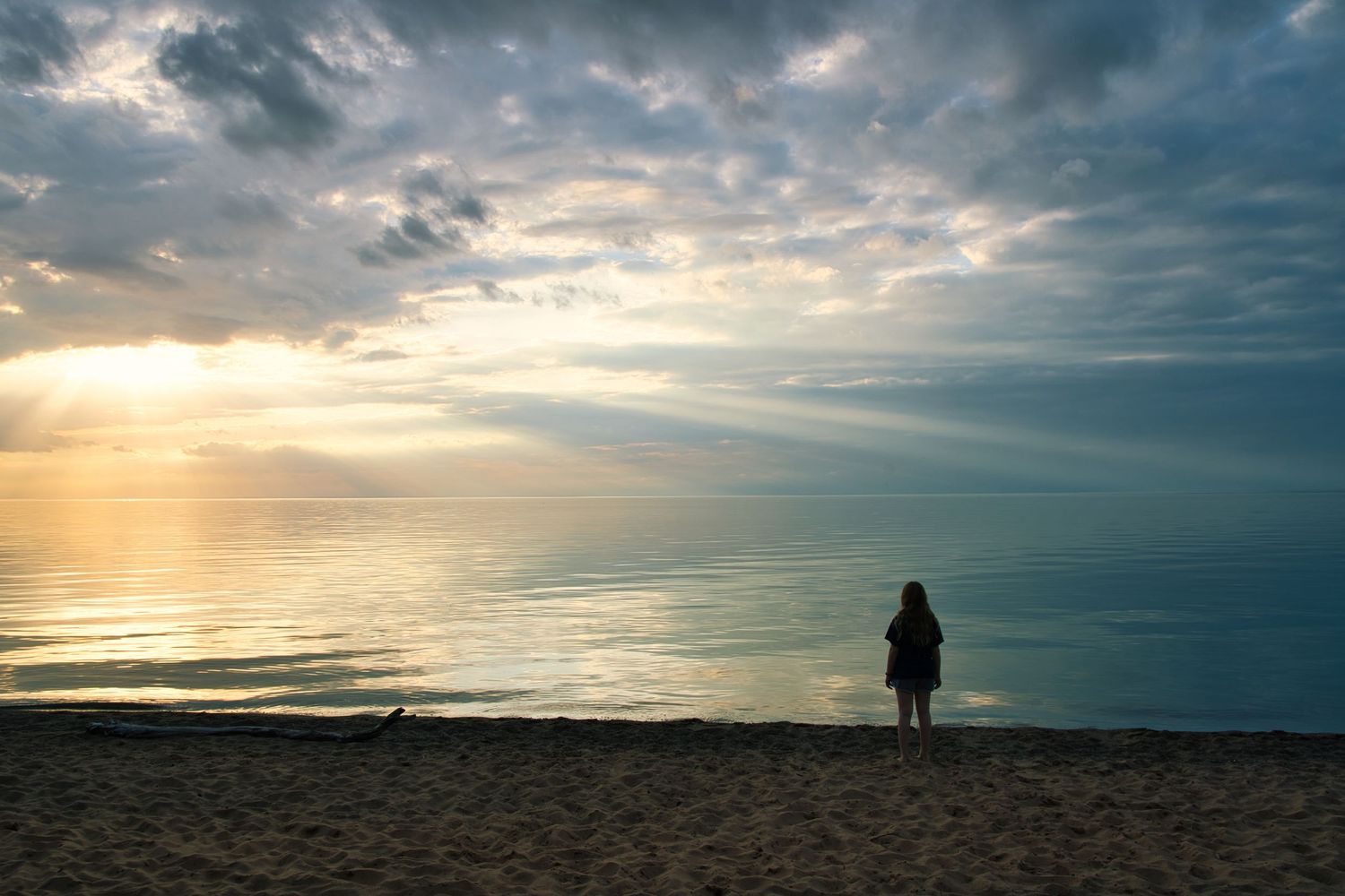 Dramatic sunset sky with silhouetted figure standing on horizon.