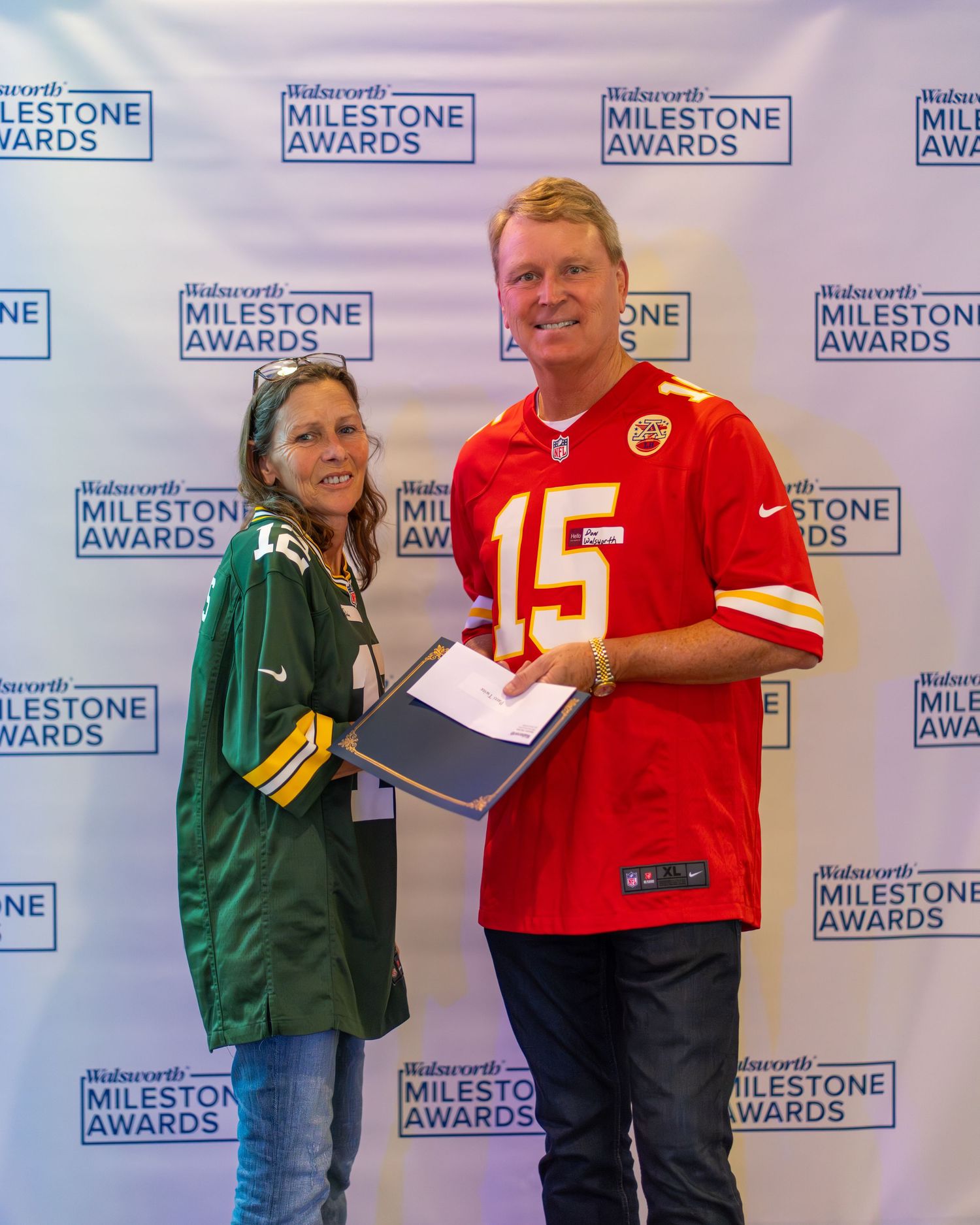 NFL fans in alternating red and green jerseys line up against a backdrop with Milestone Awards branding.