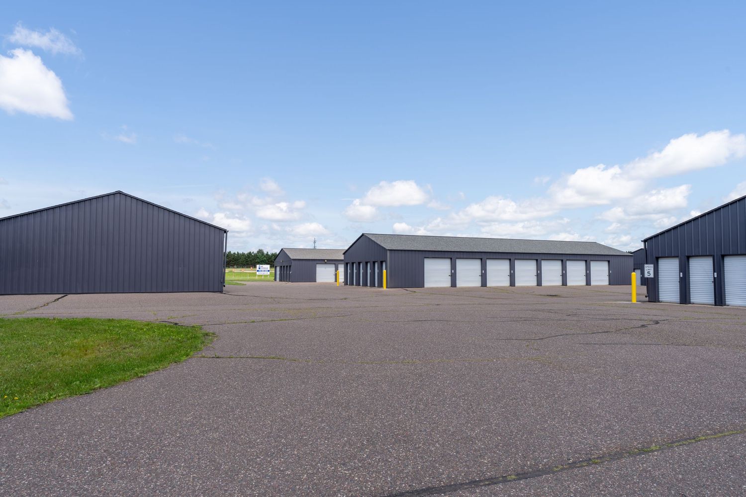 Panoramic view of industrial storage units and warehouses with metal siding against a blue sky with white clouds.