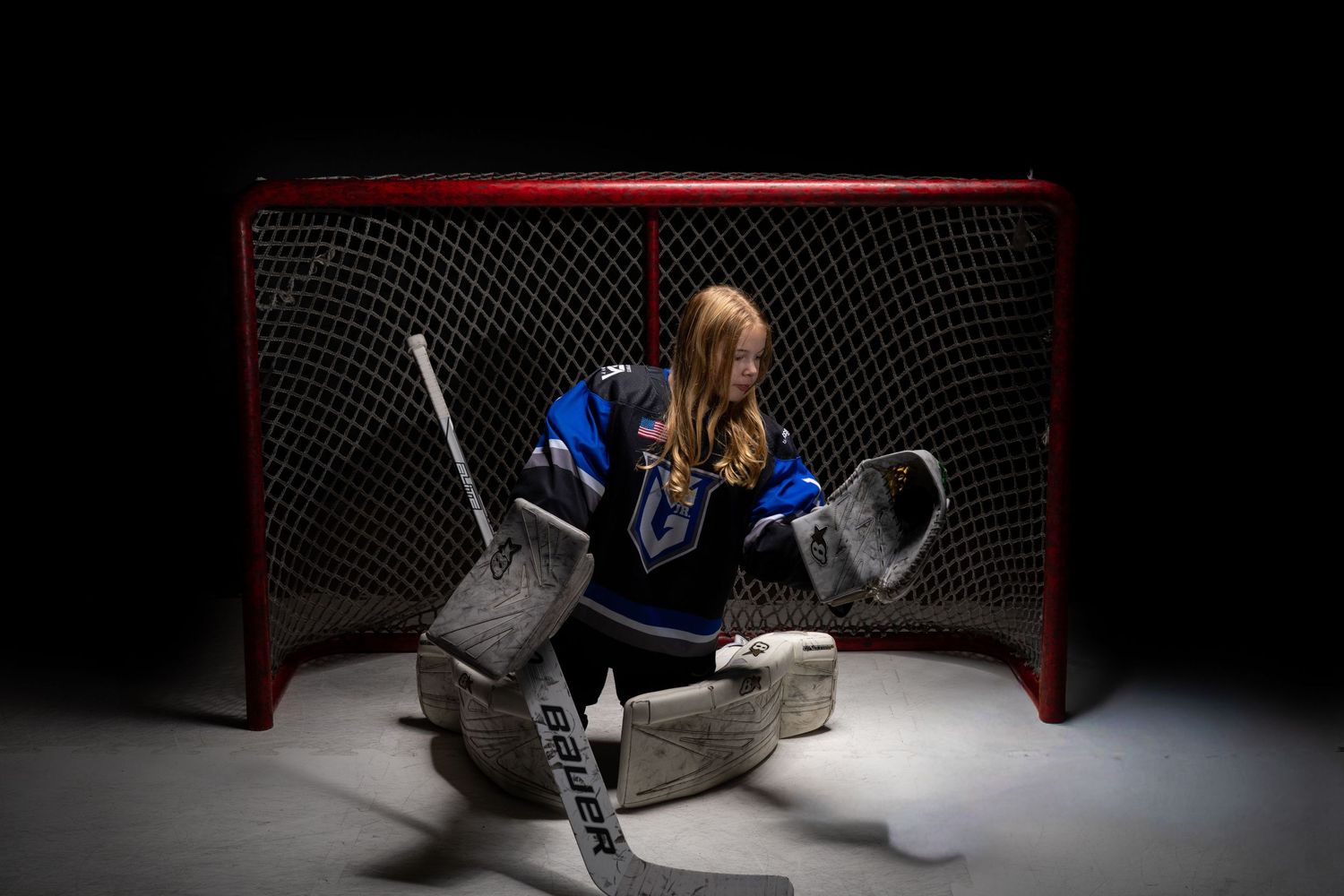 A hockey goalie makes a dramatic save while diving across the goal crease during an intense game.
