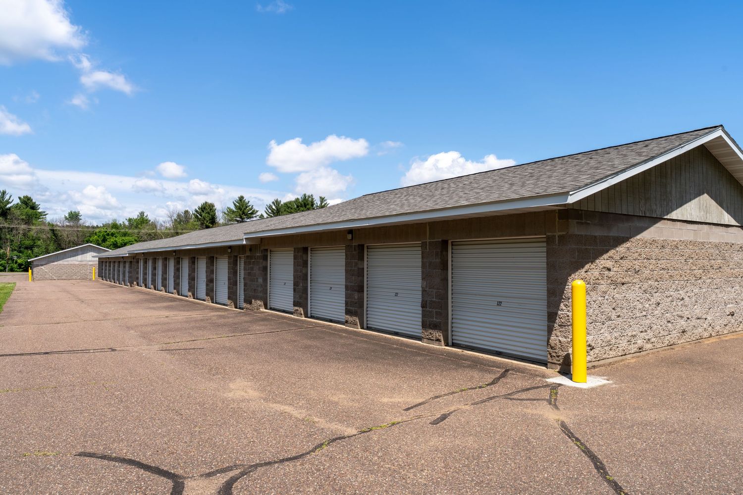 Long line of self-storage garages with white doors and brown exterior extending into the distance.