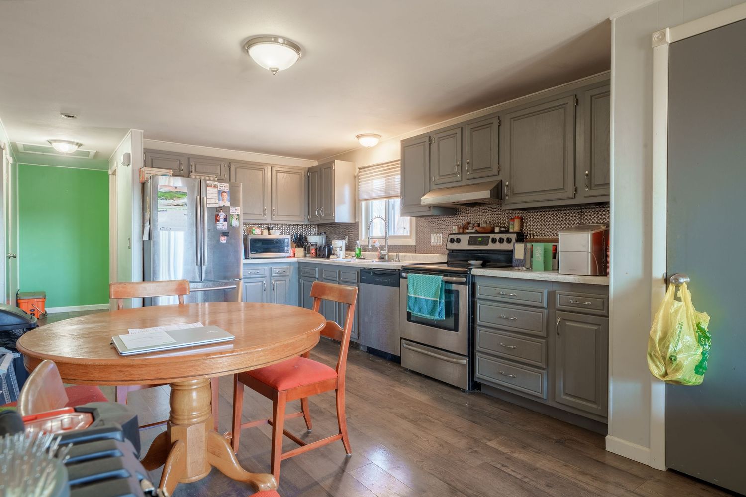 Spacious open floor plan showing kitchen with gray cabinets connecting to dining and living areas.