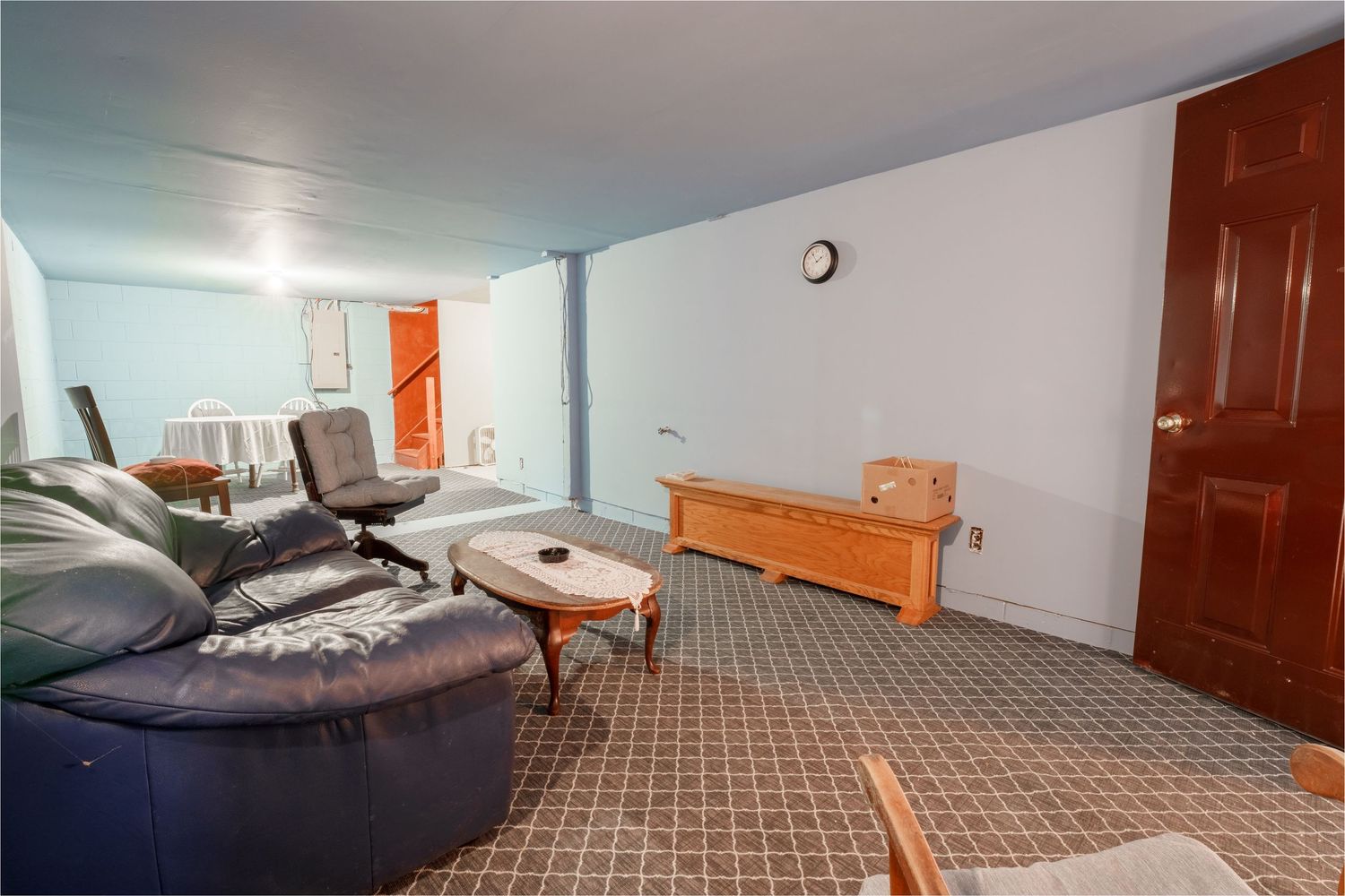 Interior view of a carpeted bedroom with orange wooden headboard and brown door.