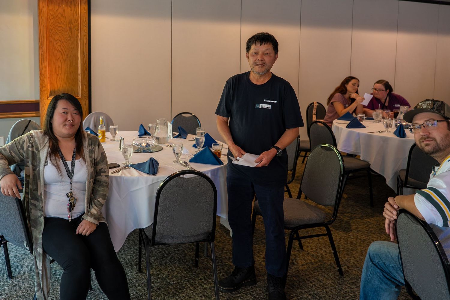 Attendees participating in a professional development session at round tables with blue napkins.
