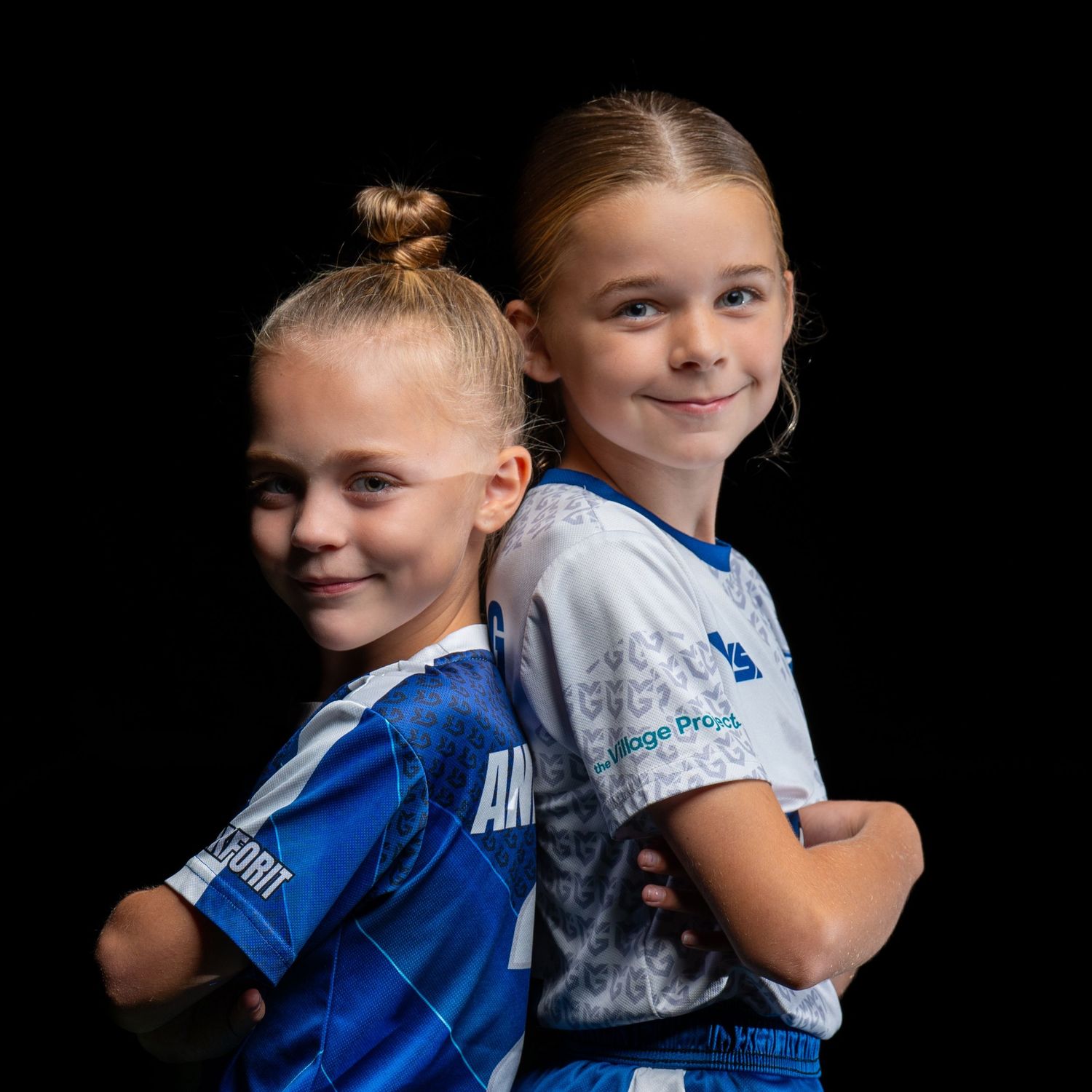 Two youth soccer players in blue jerseys pose together for team photo.