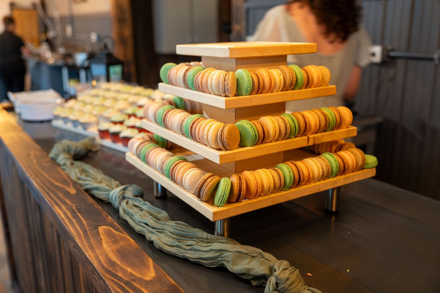 Colorful macarons arranged in ascending tiers on wooden boards create an elegant dessert display.