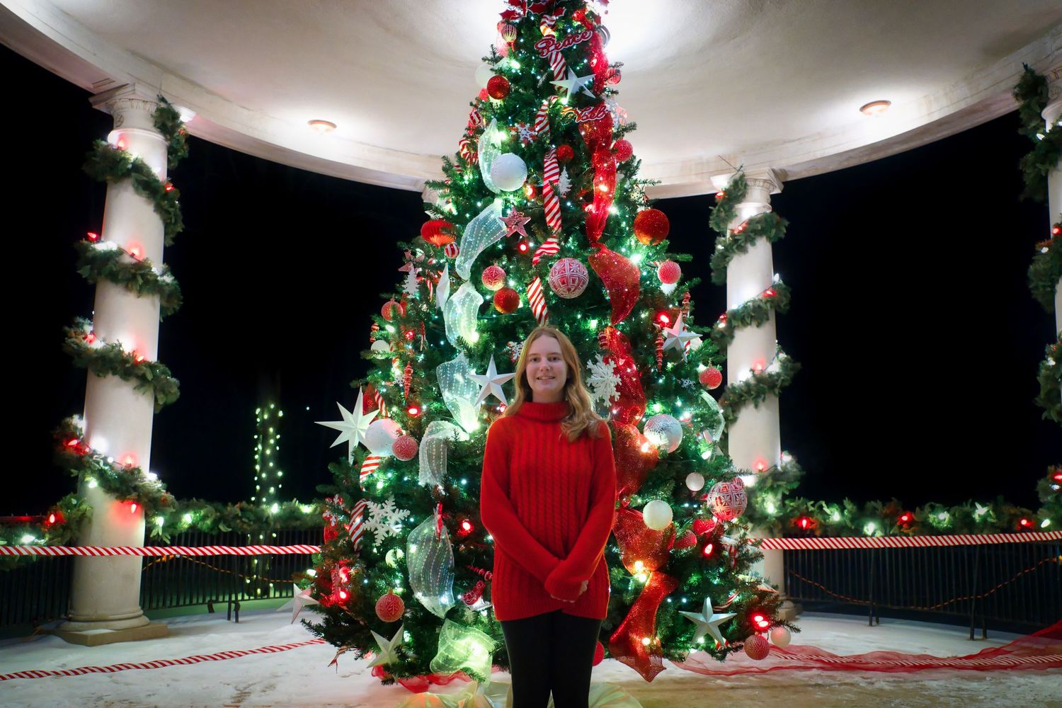 Christmas decorations and trees with red and white ornaments in an indoor setting.