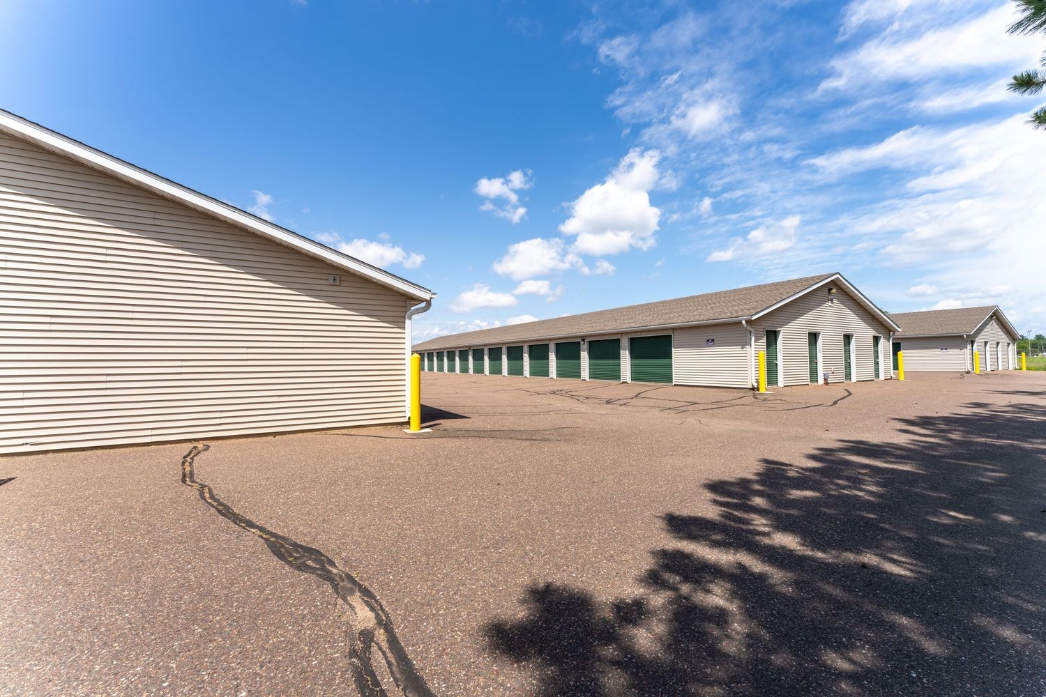 A long row of beige storage units with tan metal doors stretches across a desert landscape under blue skies.